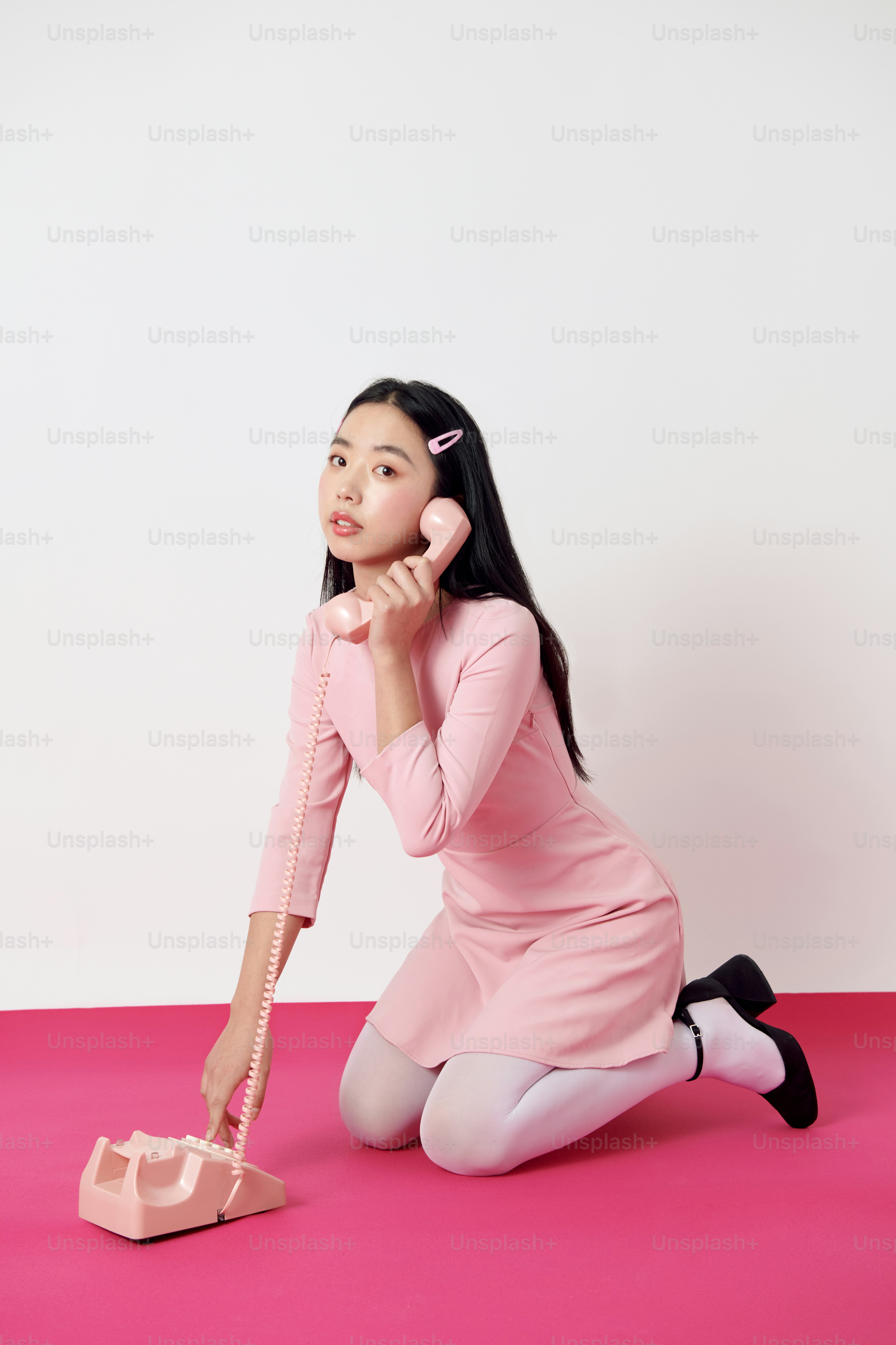 A woman sitting on the ground while talking on a cell phone