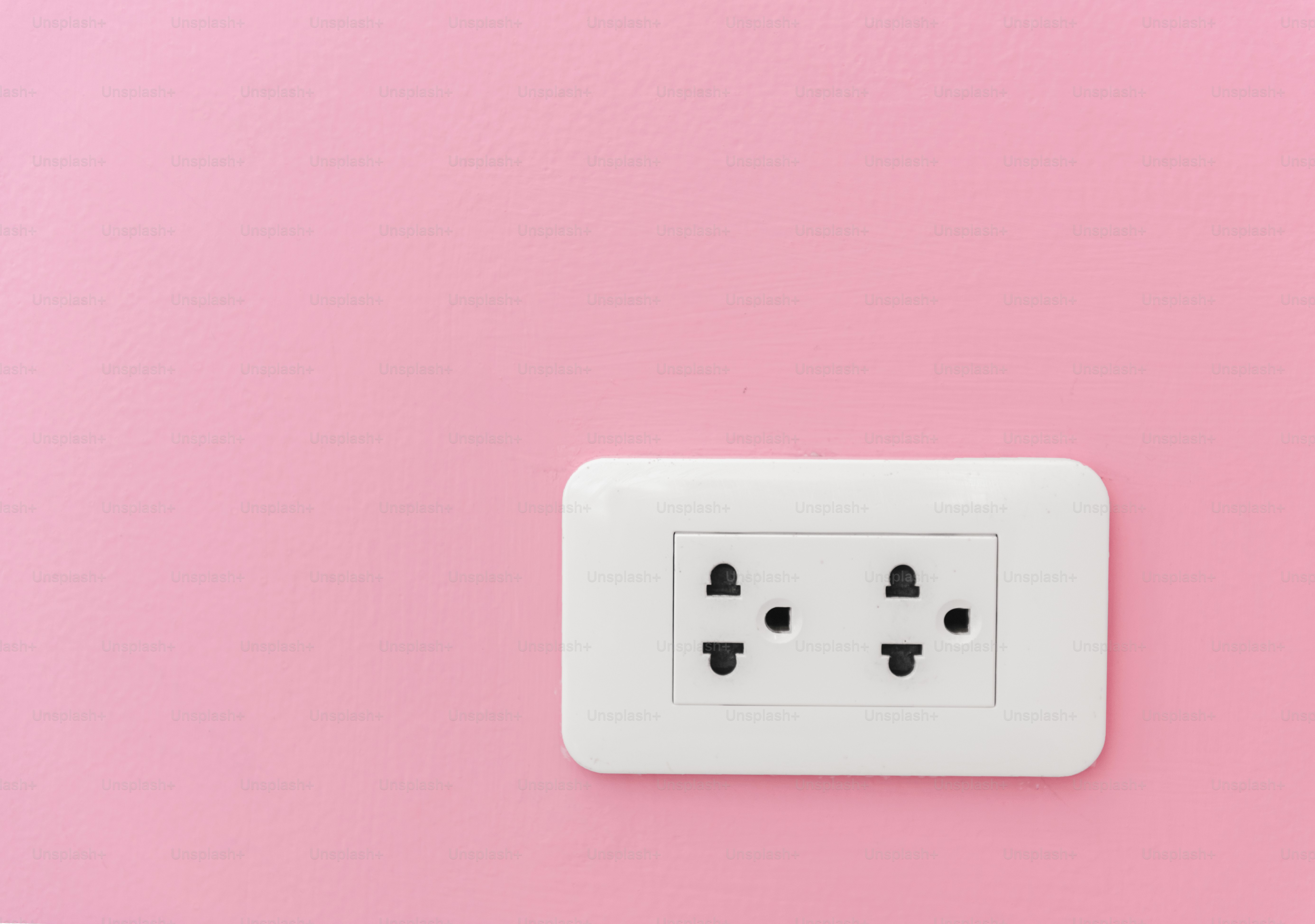 ピンクの壁の電気プラグ供給