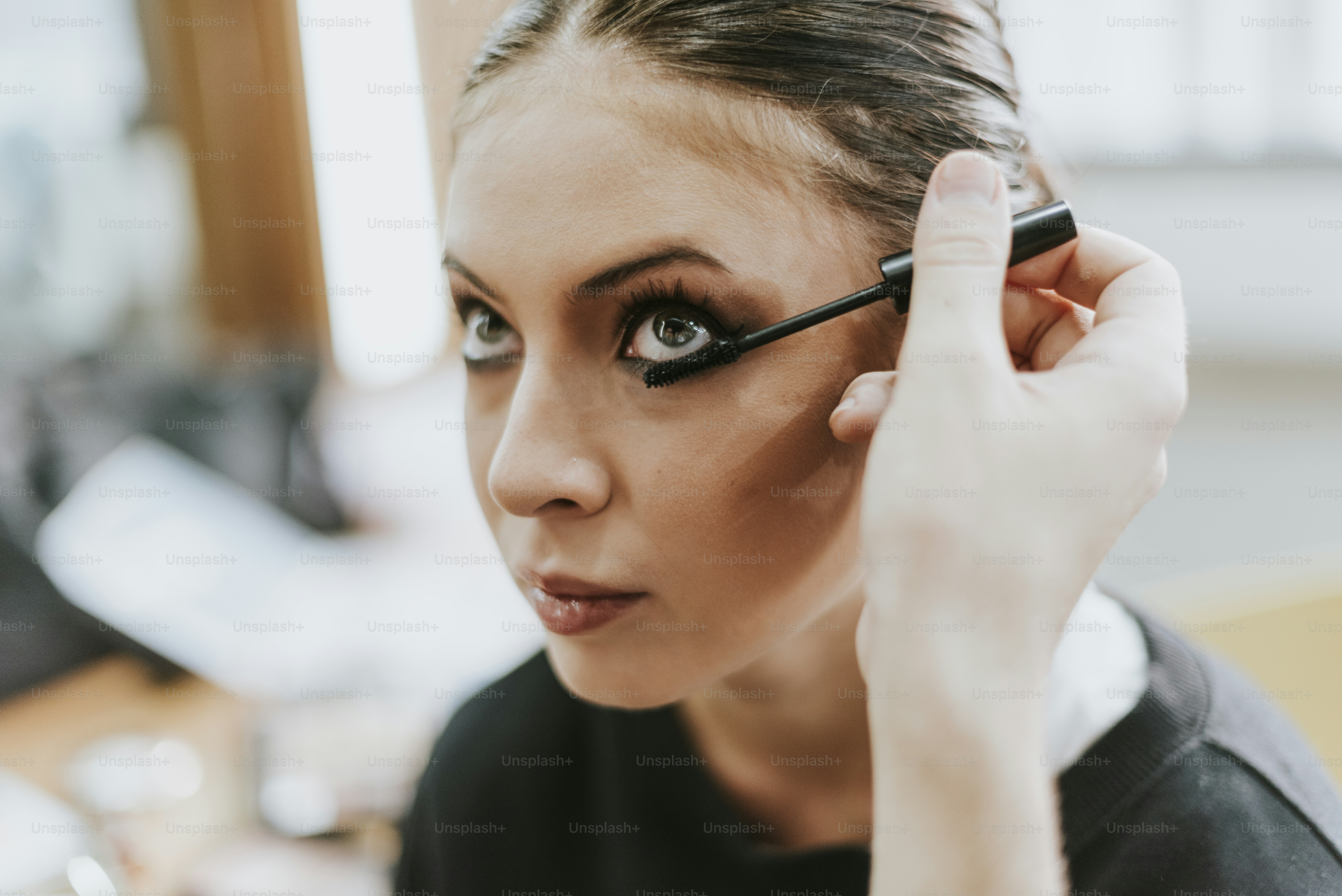 Makeup artist applying mascara onto the model