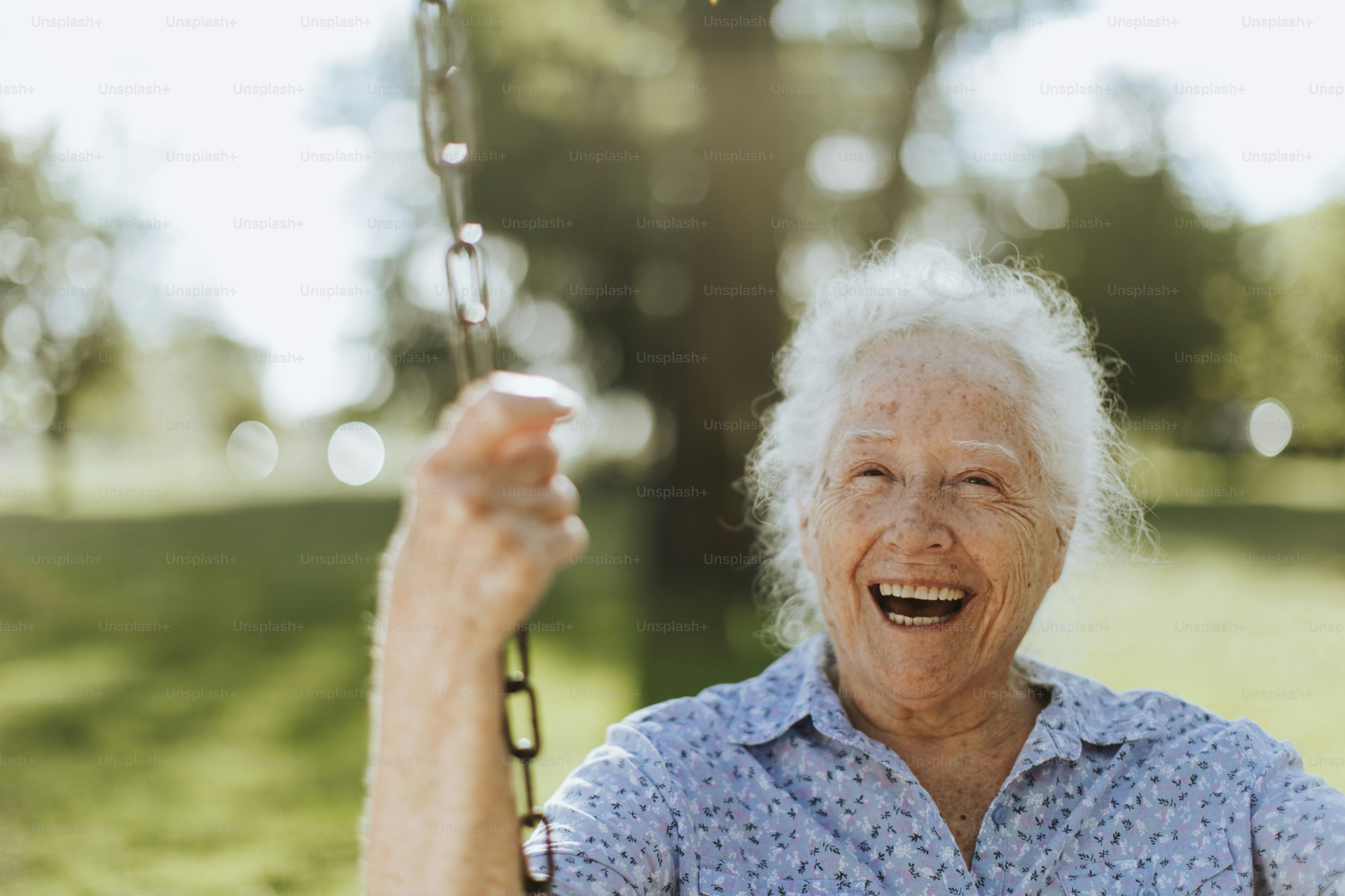 Cheerful senior woman on a swing at a playground