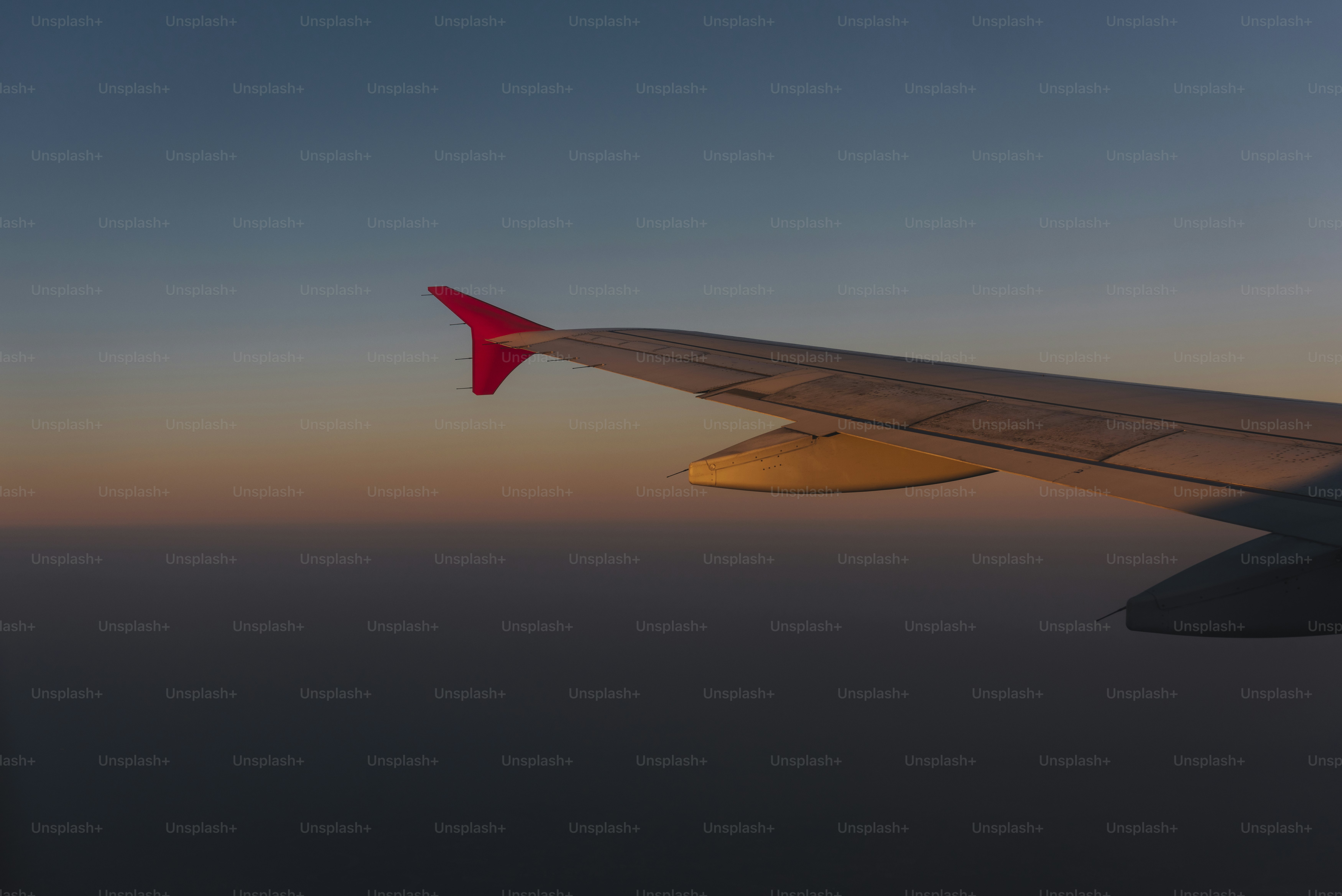 Wing of a plane flying in a dusky sky