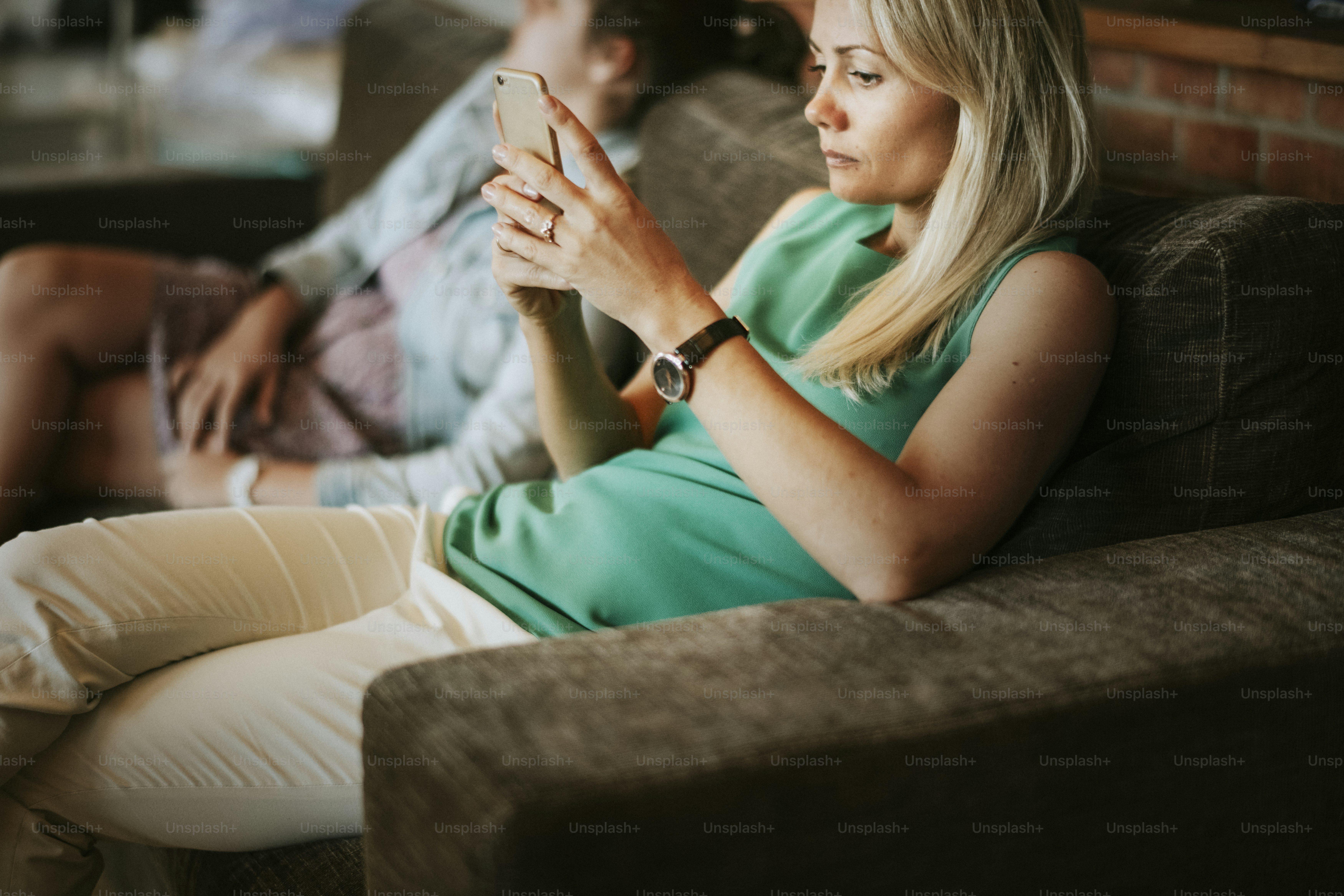 Mama benutzt ihr Handy, während sie sich auf der Couch entspannt