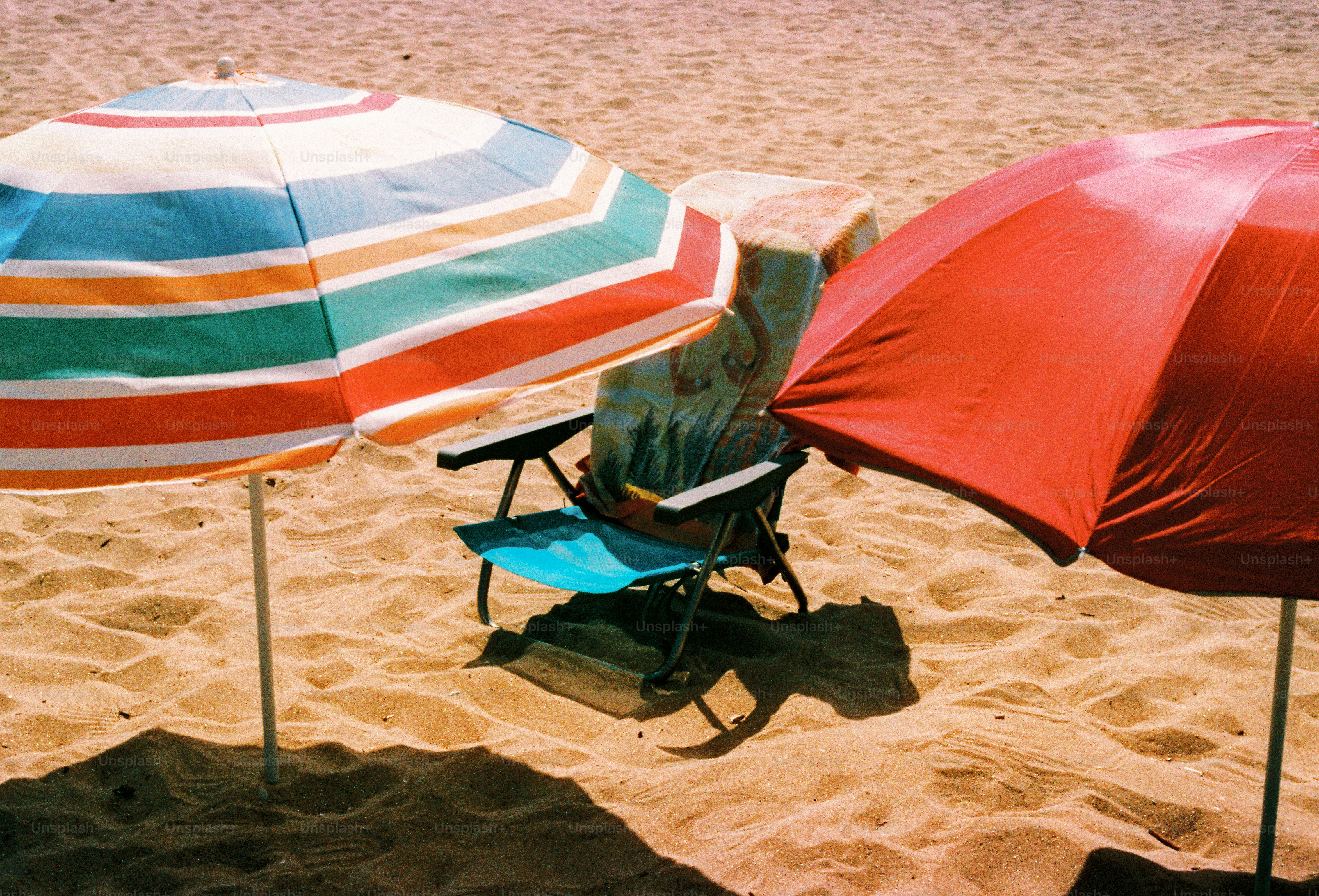 Un paio di ombrelloni che sono seduti nella sabbia