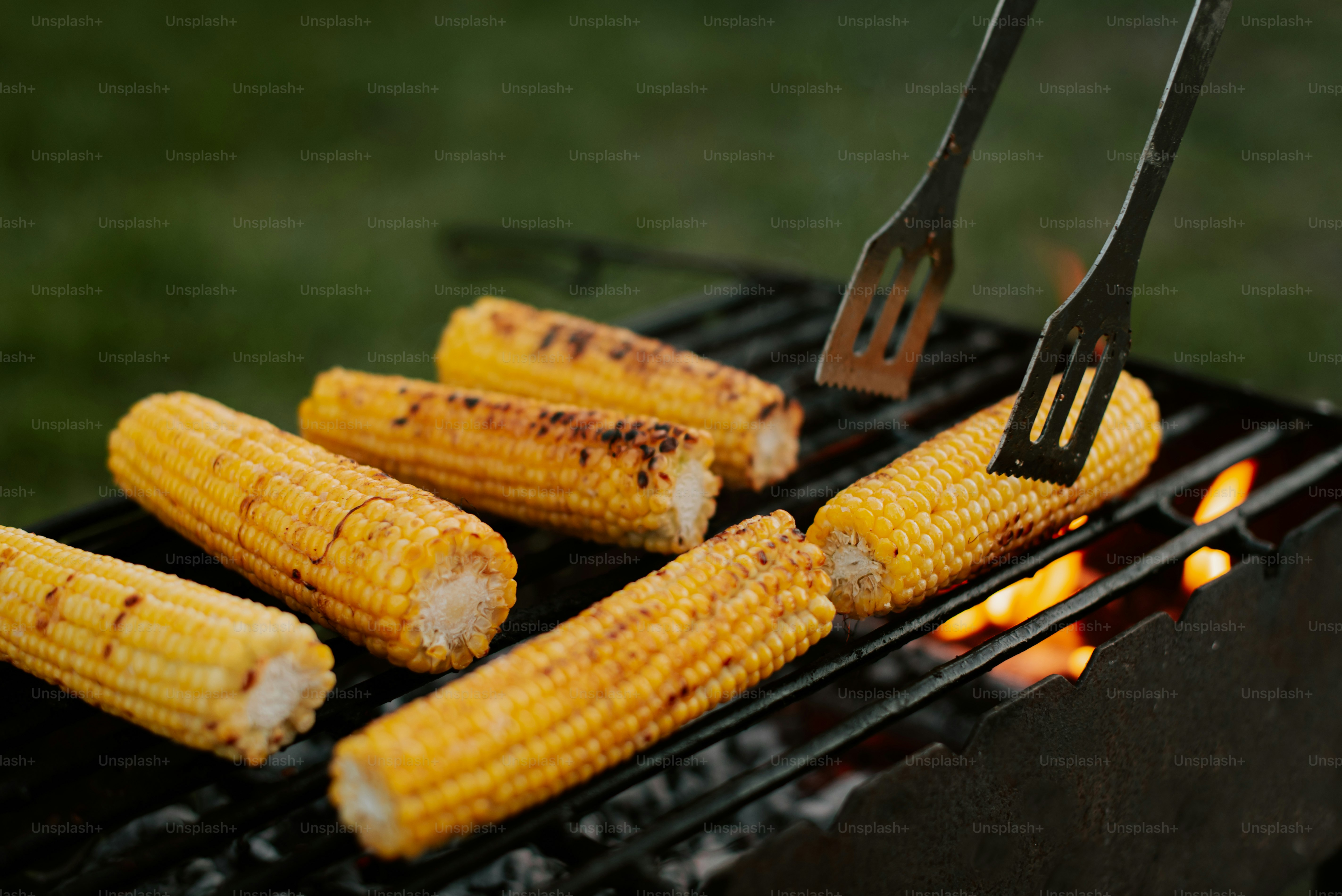 A grill with corn on the cob and a spatula