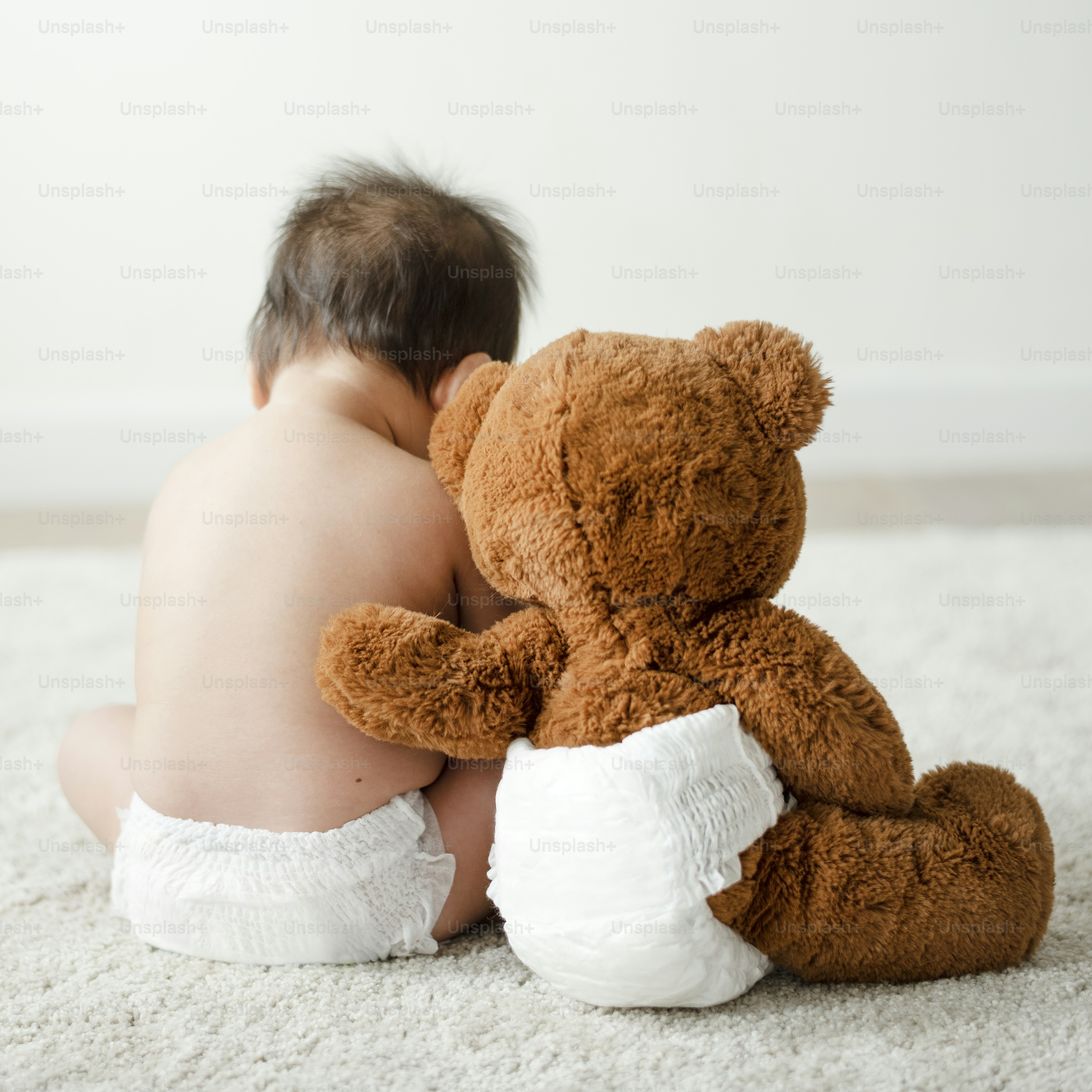 Back of a baby with a teddy bear