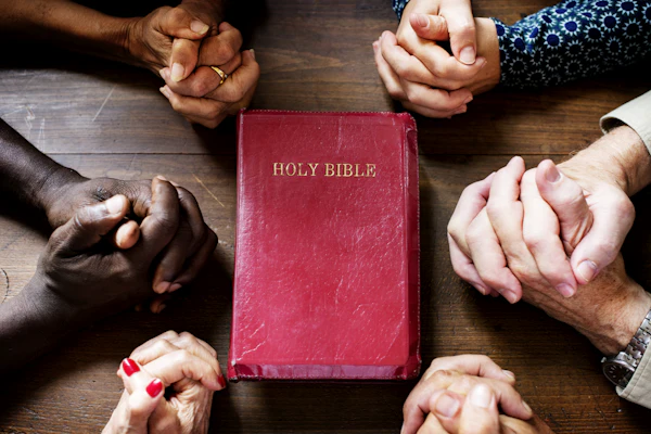 Group of adults holding small bibles conversing in living room