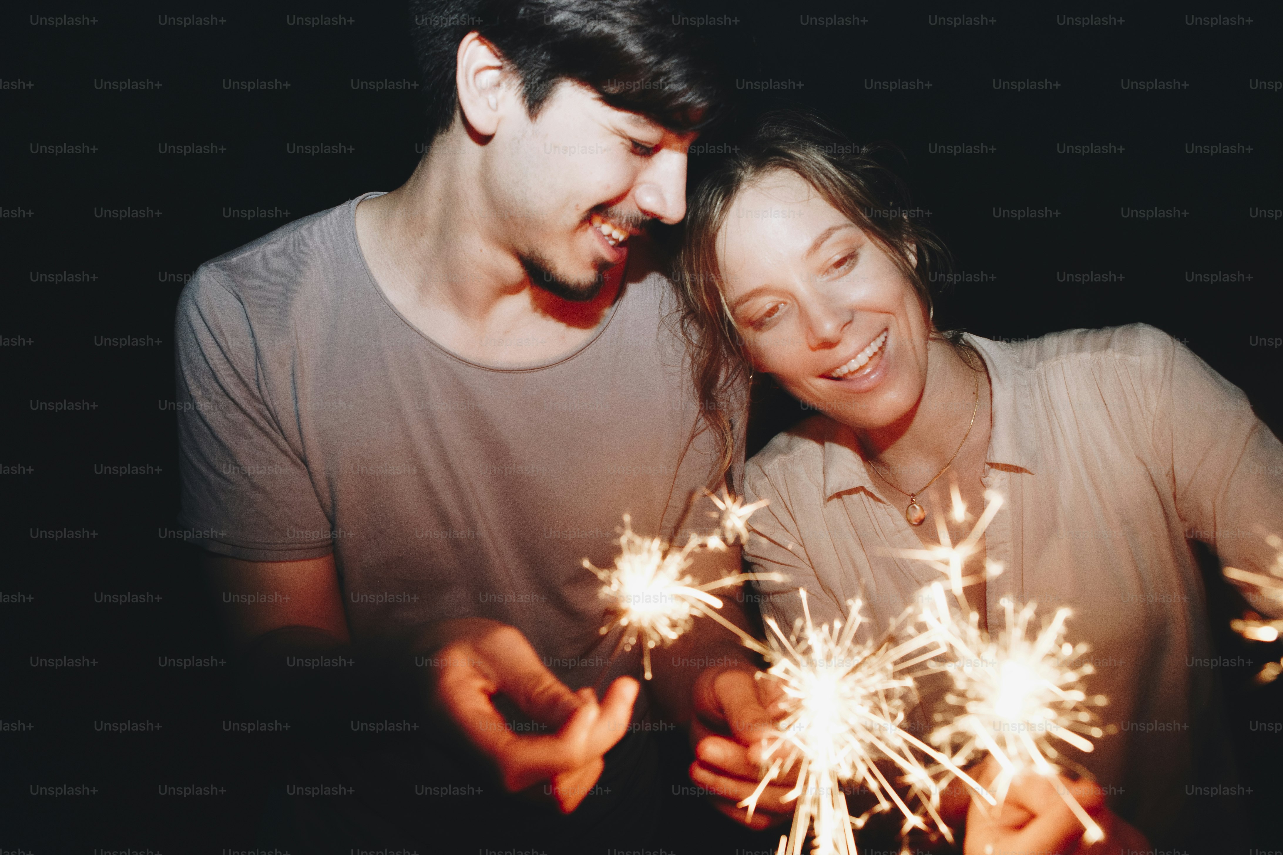 Caucasian man and woman couple playing with sparklers celebration and festive party concept