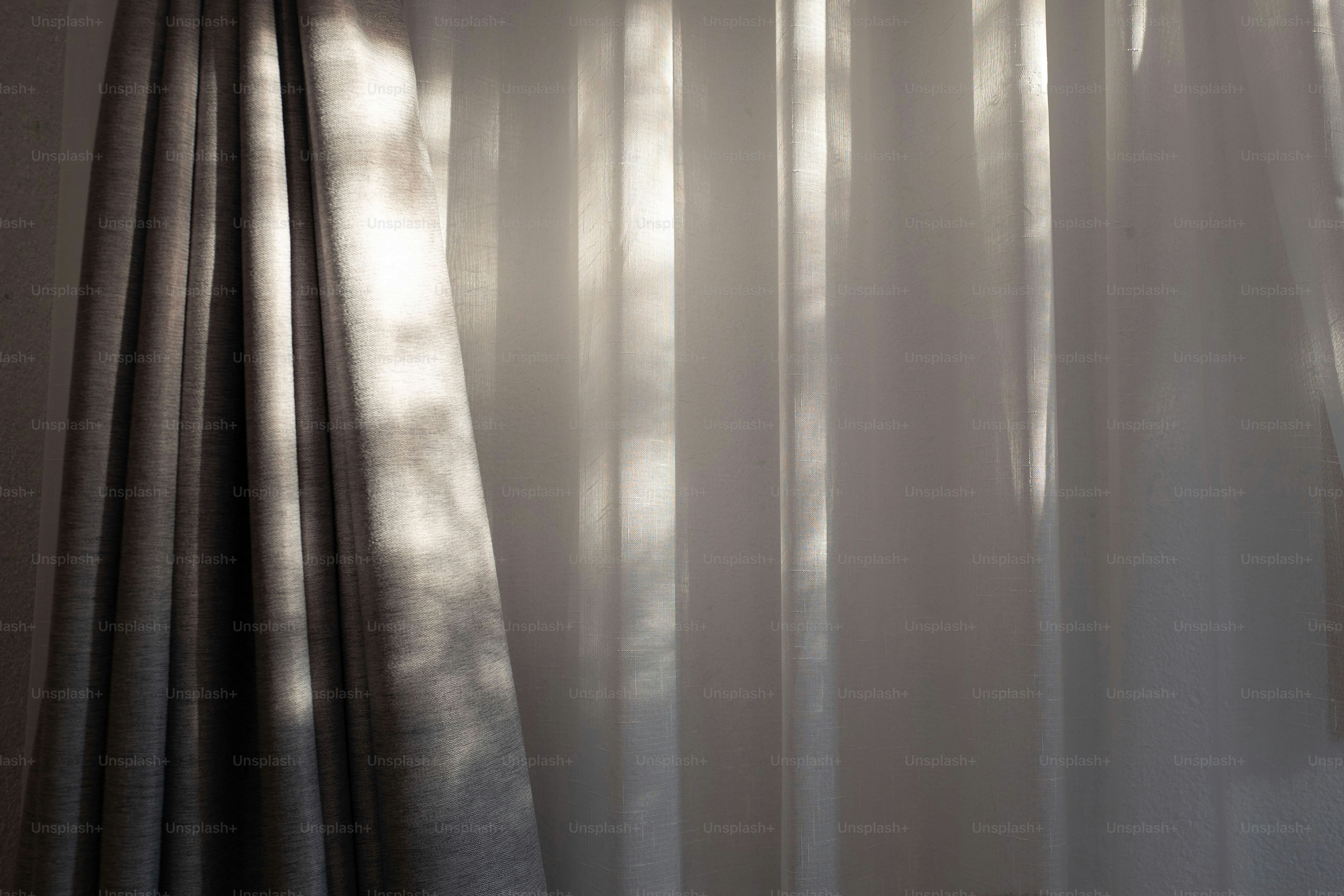 A room with a curtain and a window with sunlight coming through it ...