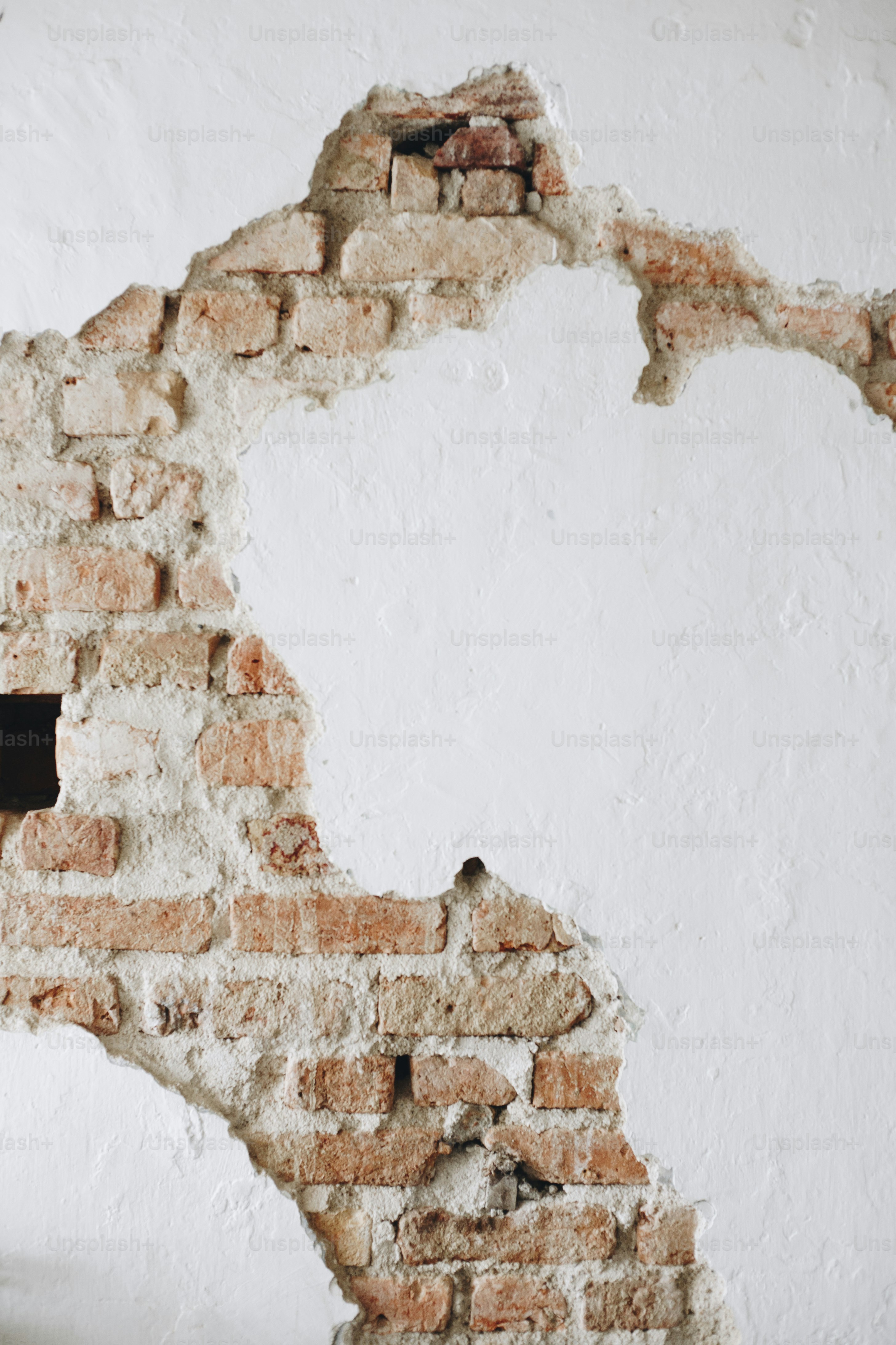 Eine rissige weiße Betonwand mit Ziegeln
