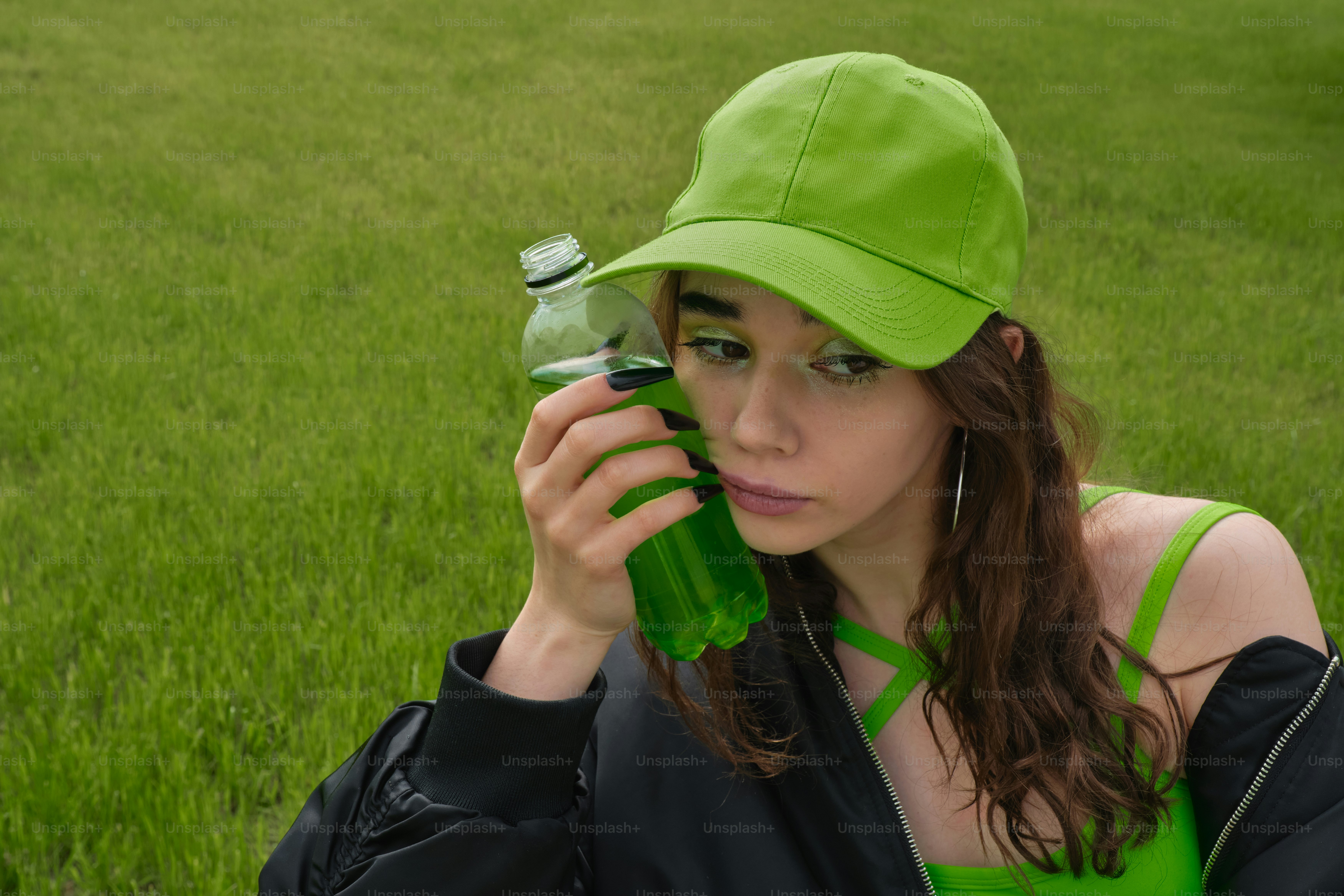 緑の帽子をかぶった女性が緑のボトルを持っているの写真 – Unsplashの 