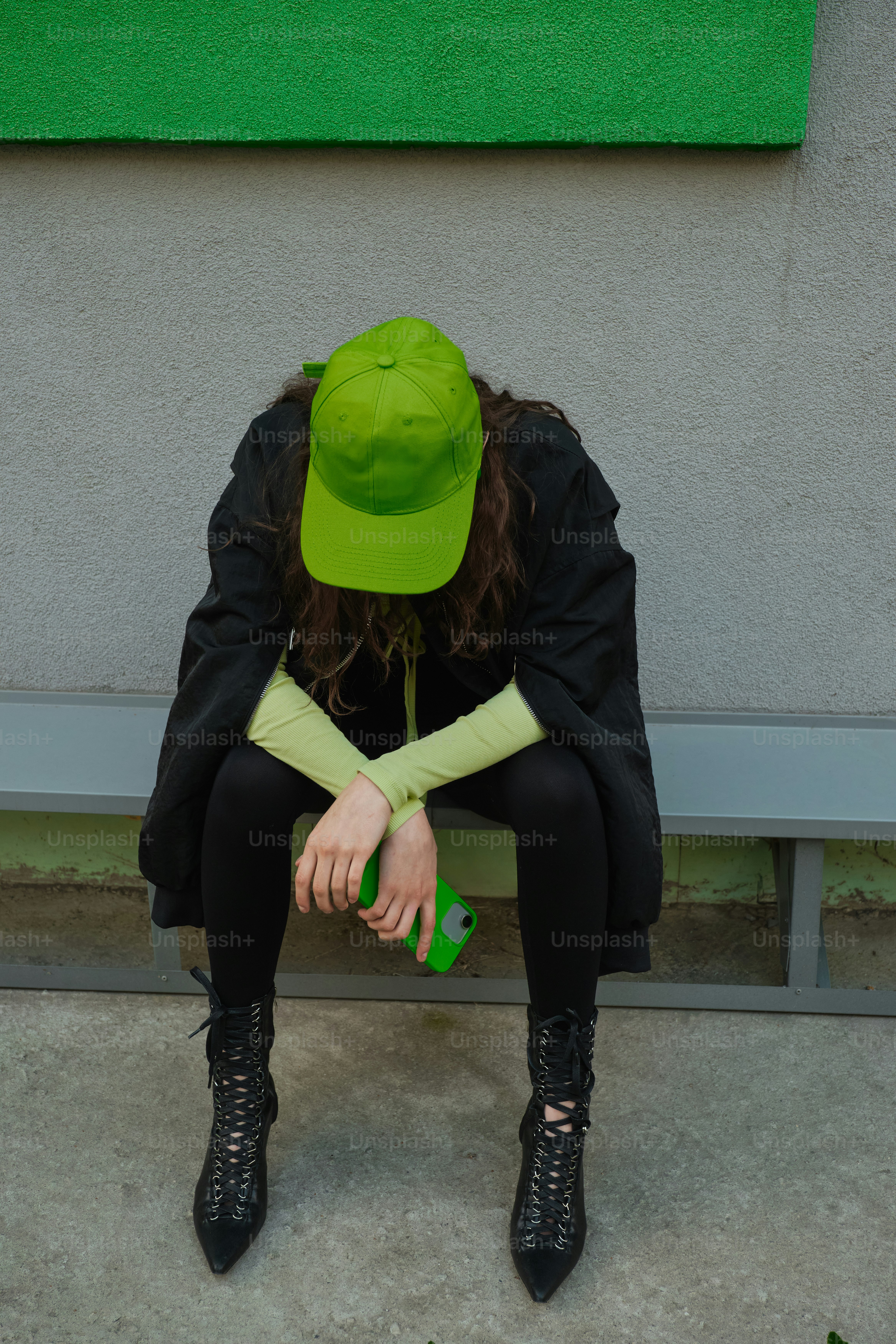 Una donna con un cappello verde seduta su una panchina