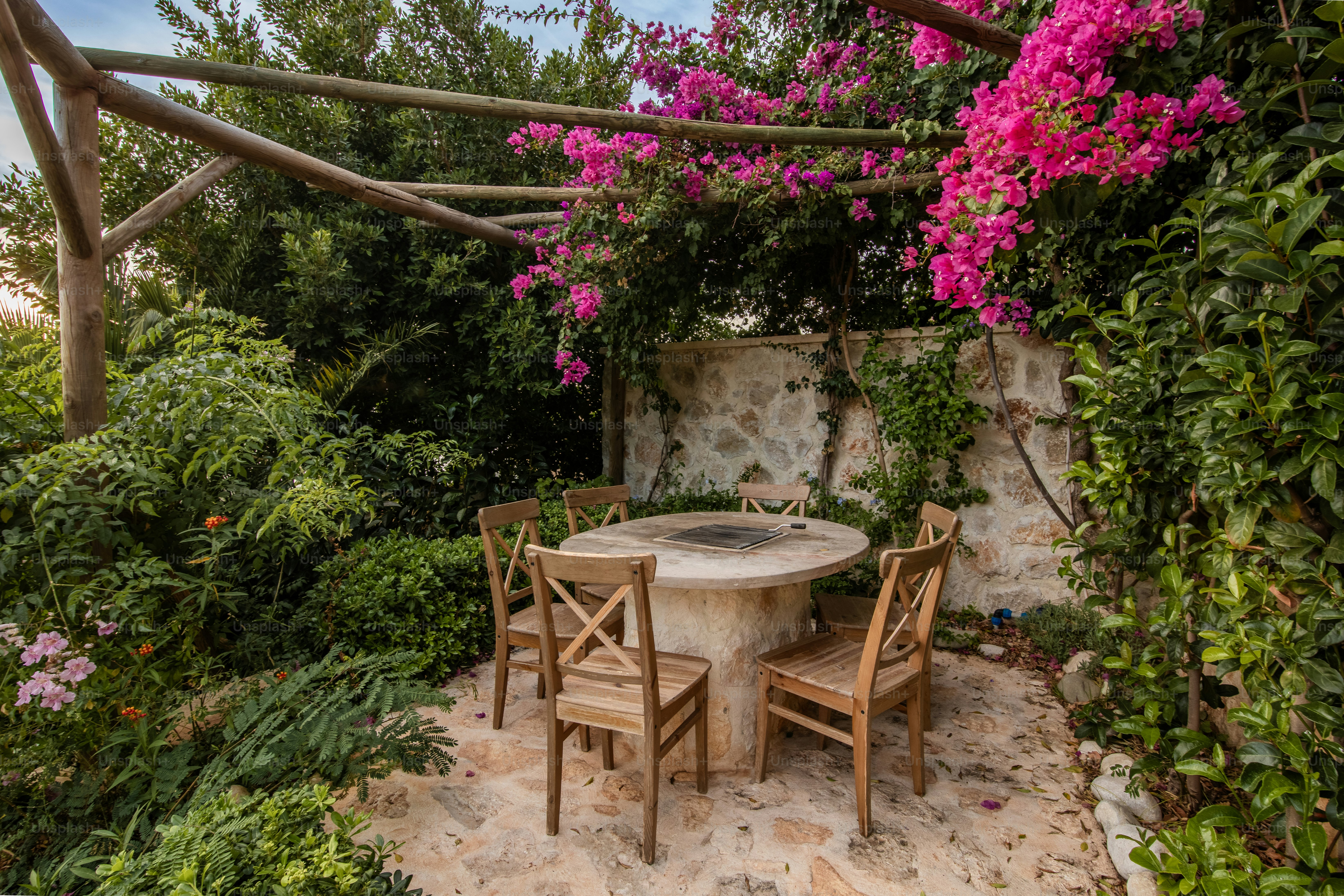 A patio with a table and chairs surrounded by flowers