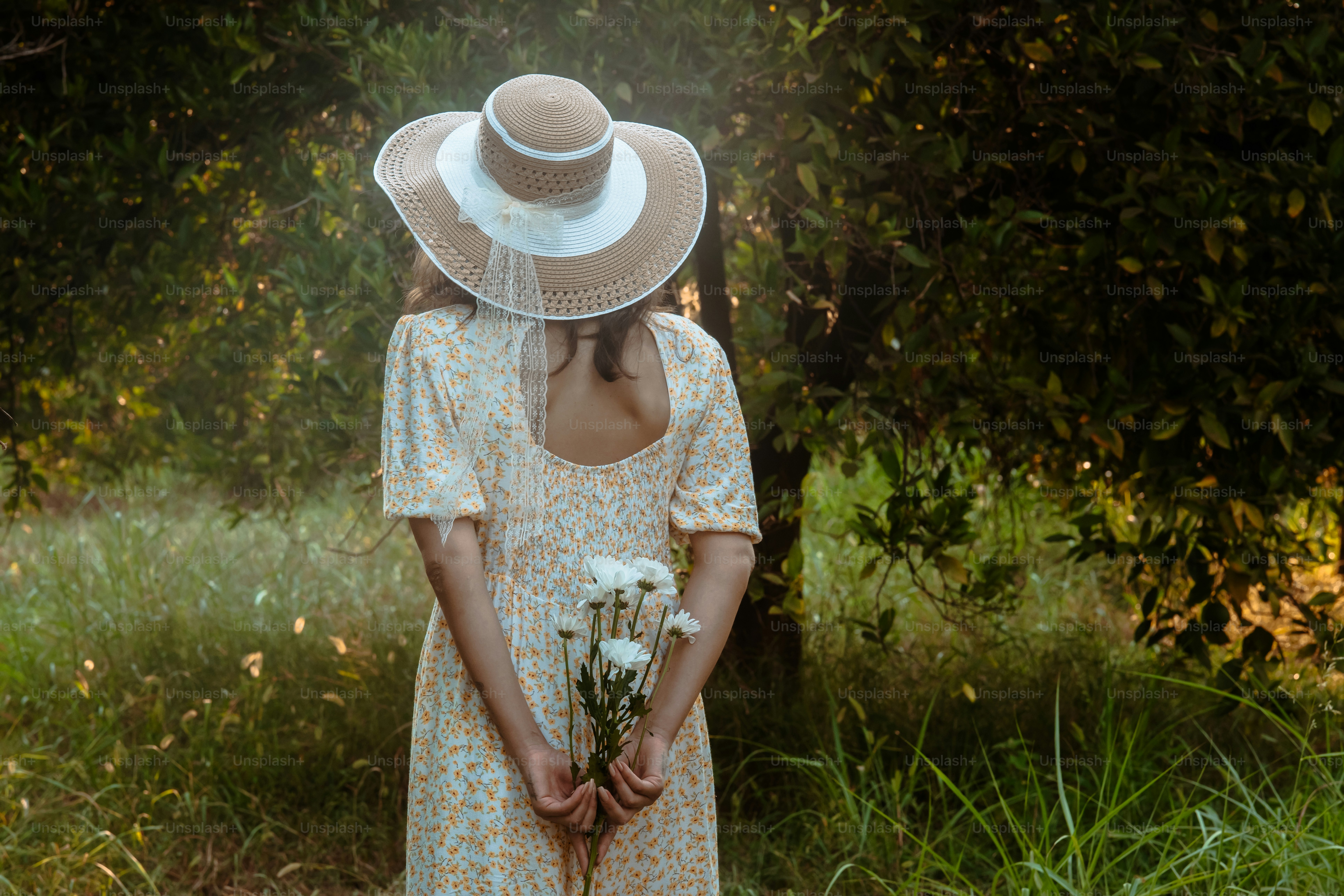 A woman in a dress and hat holding a bouquet of flowers