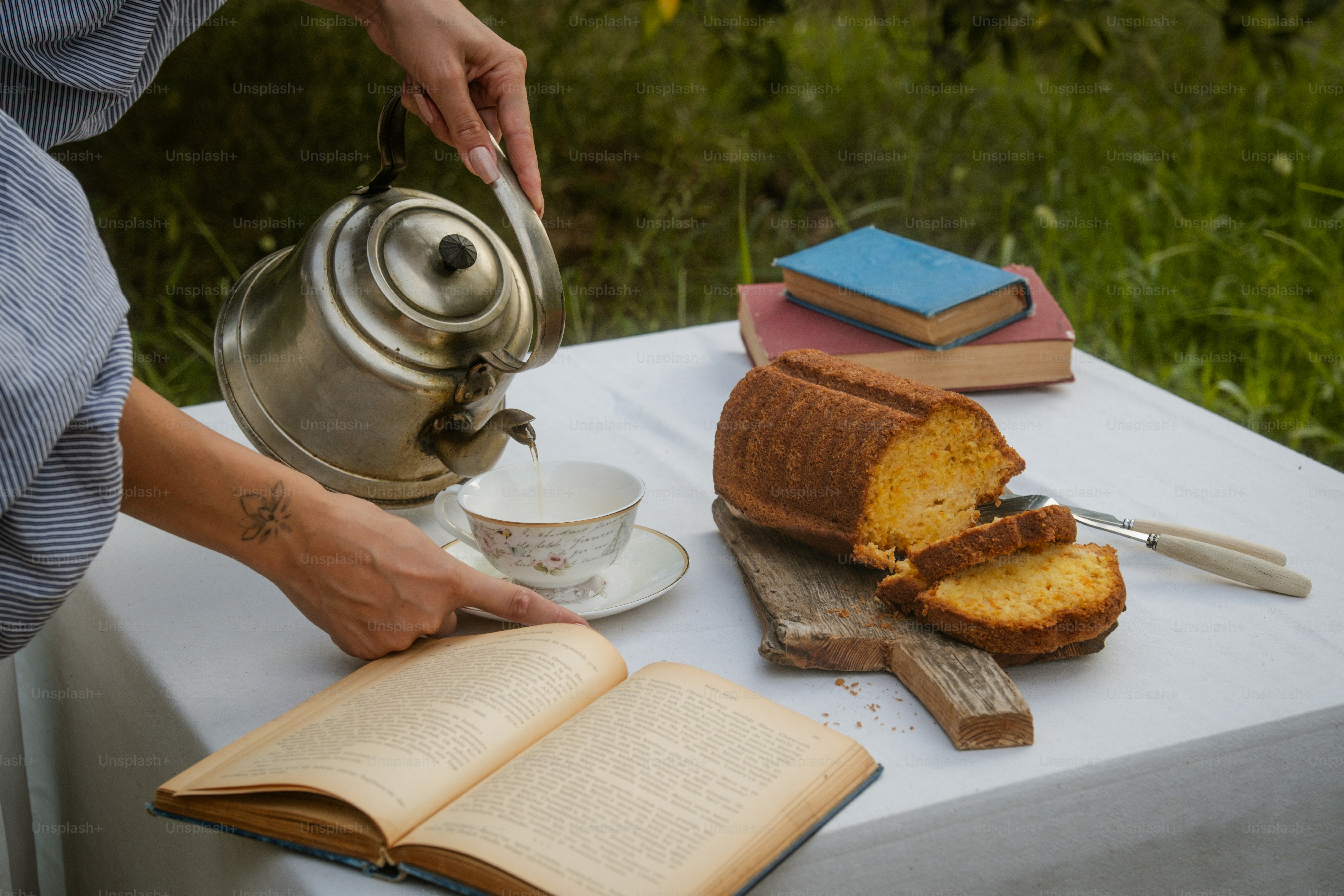 A person pouring tea from a teapot on a table