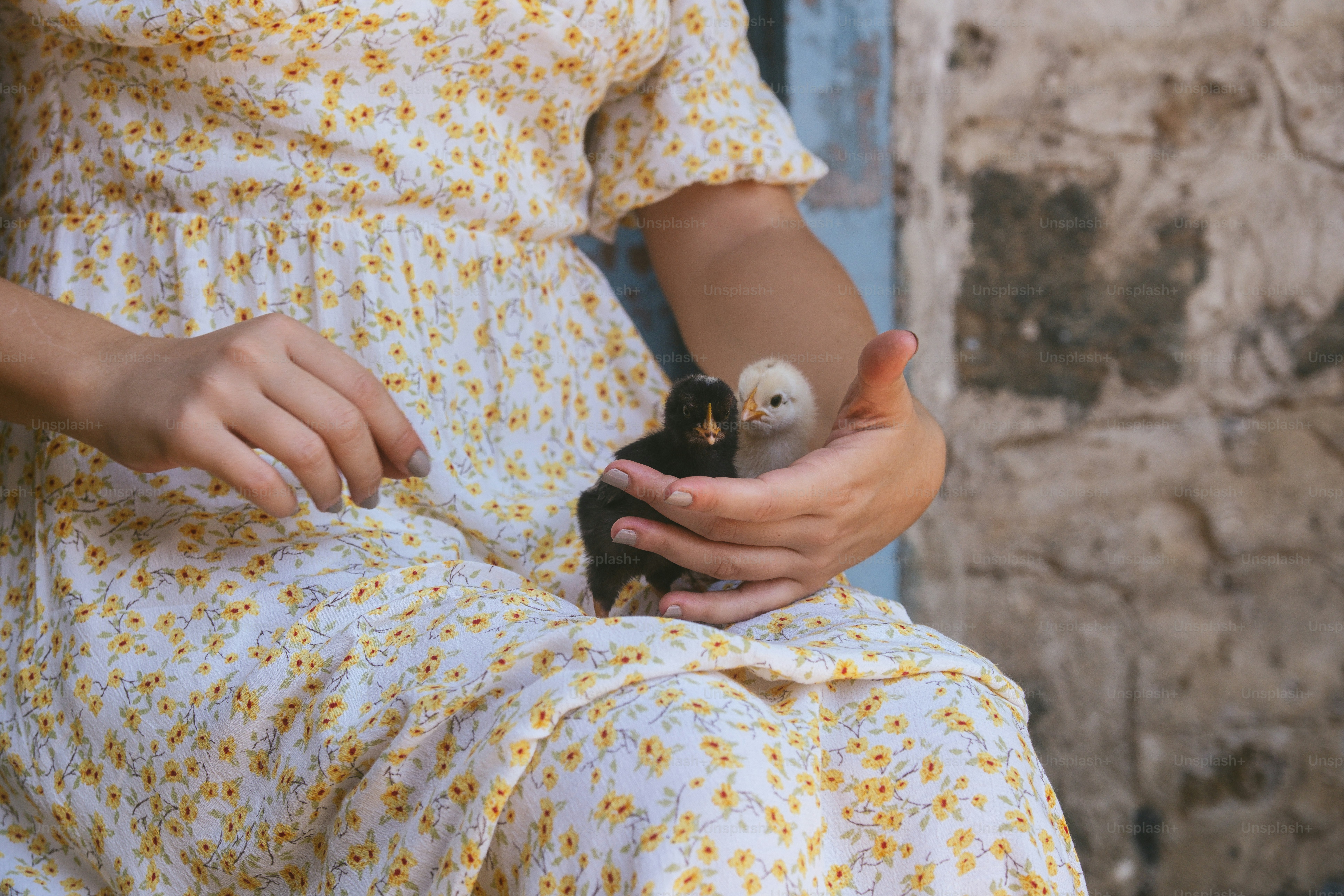 A woman in a yellow dress holding a small bird