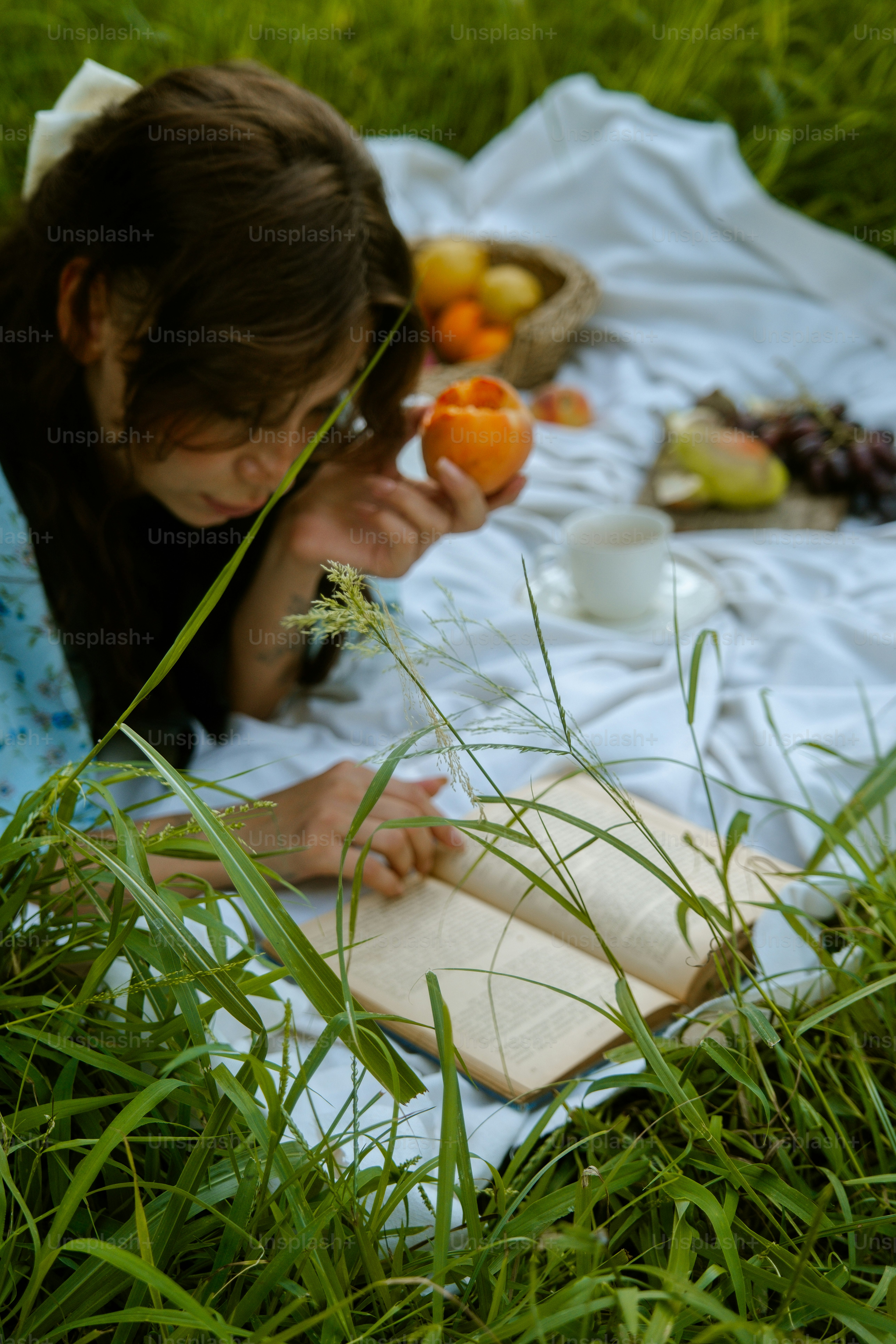A woman laying in the grass reading a book