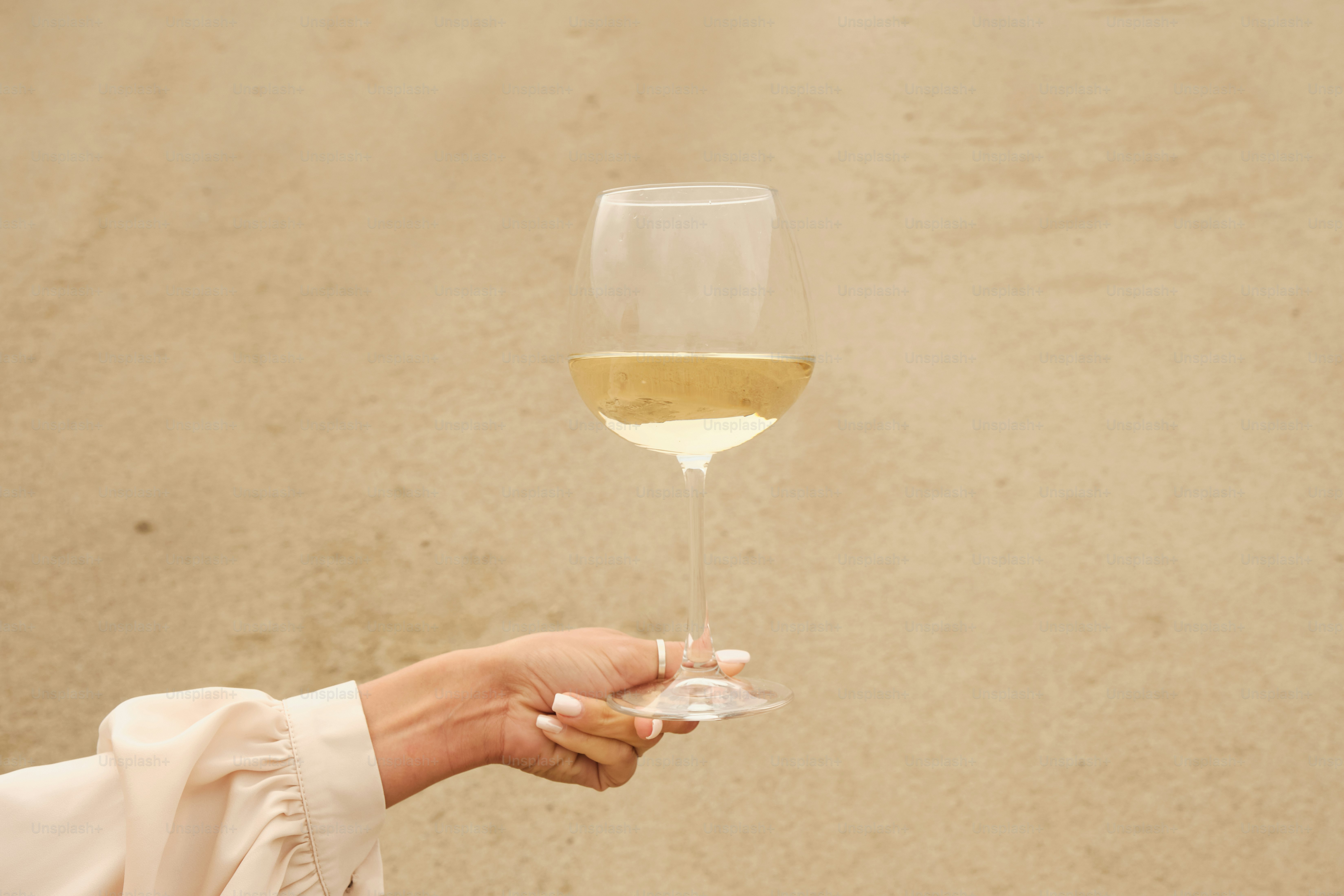 Una mujer sosteniendo una copa de vino blanco