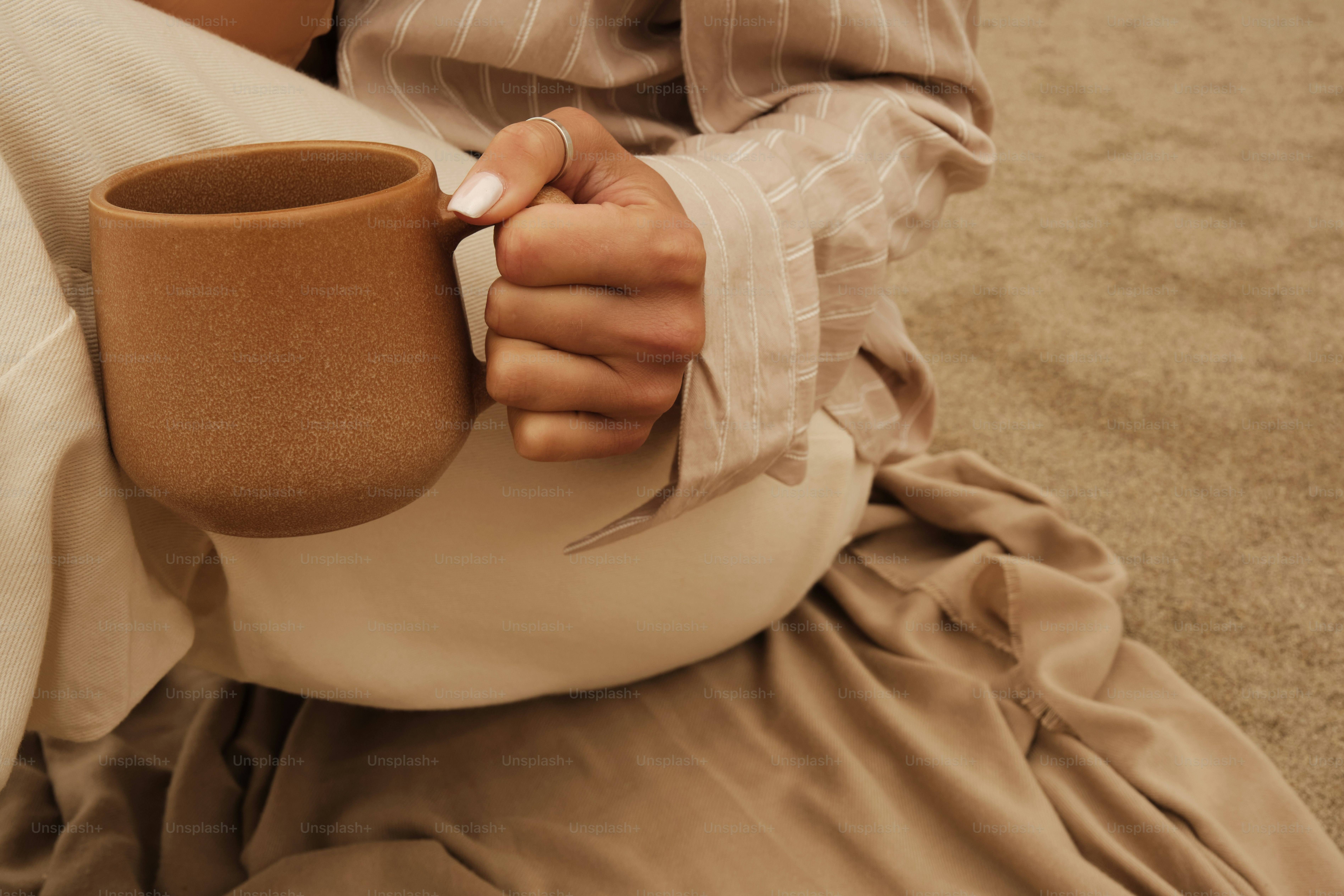 A woman sitting on the ground holding a coffee cup