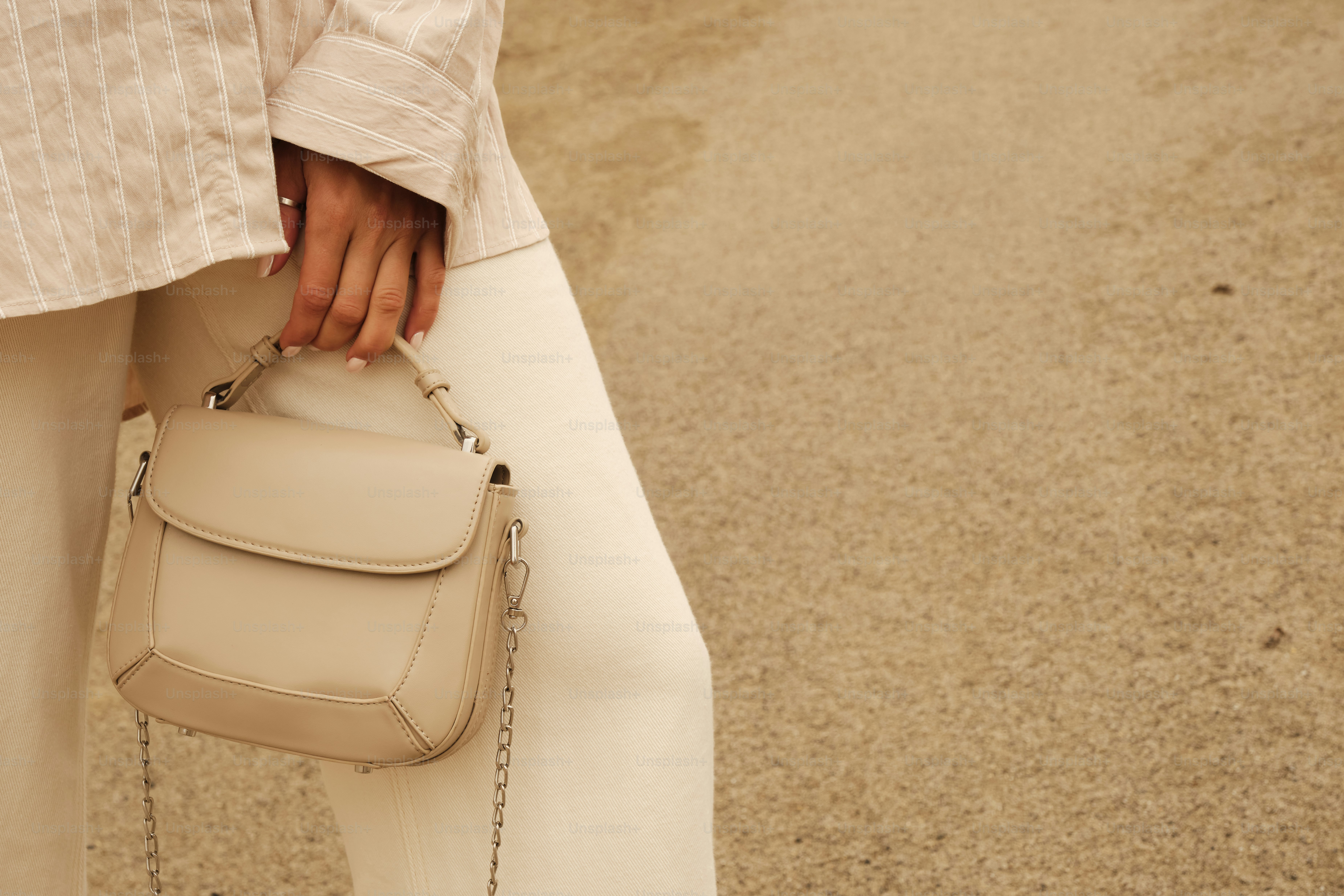A woman in white pants holding a white purse