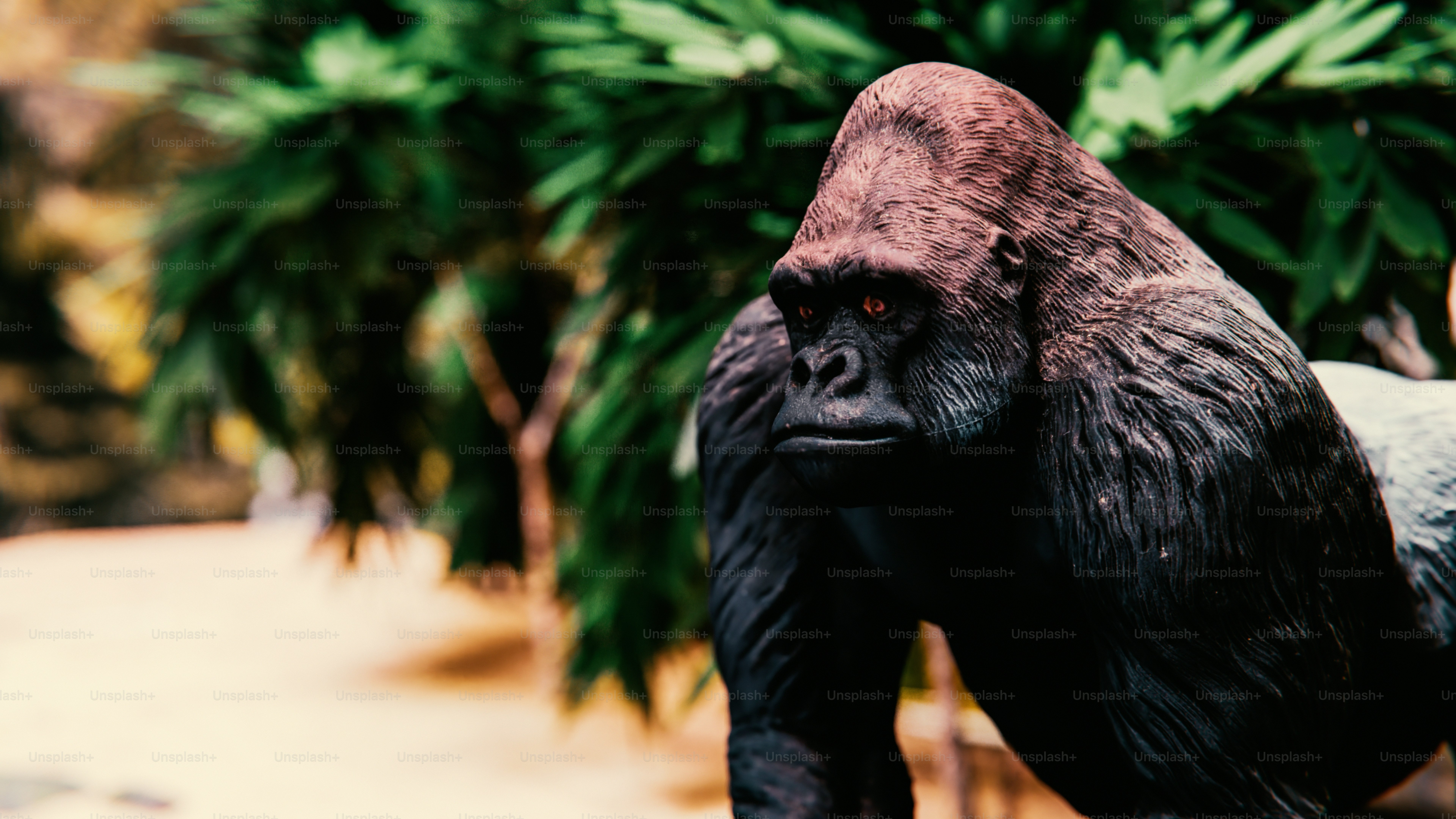A statue of a gorilla standing next to a tree