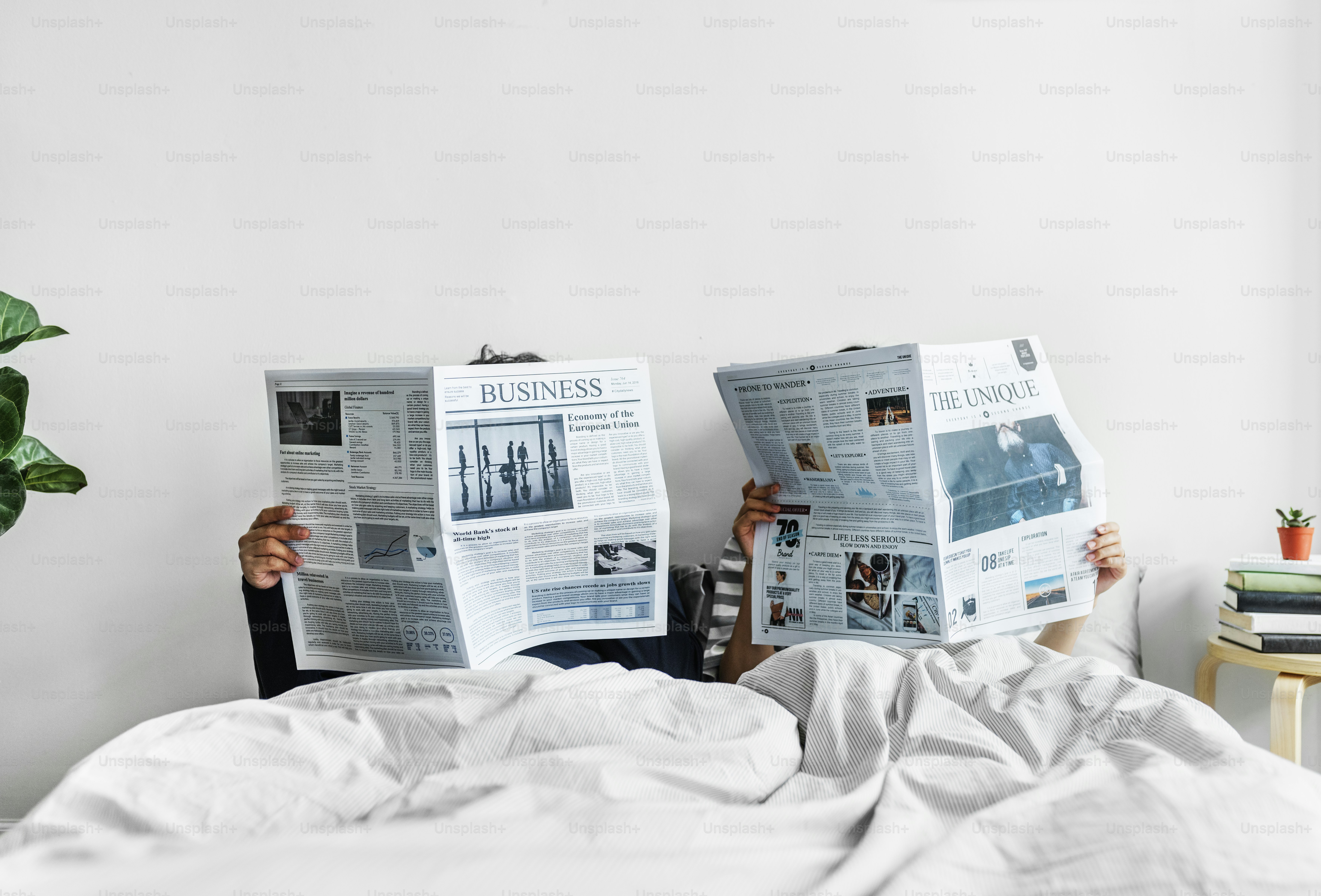 Asian couple reading newspapers in bed