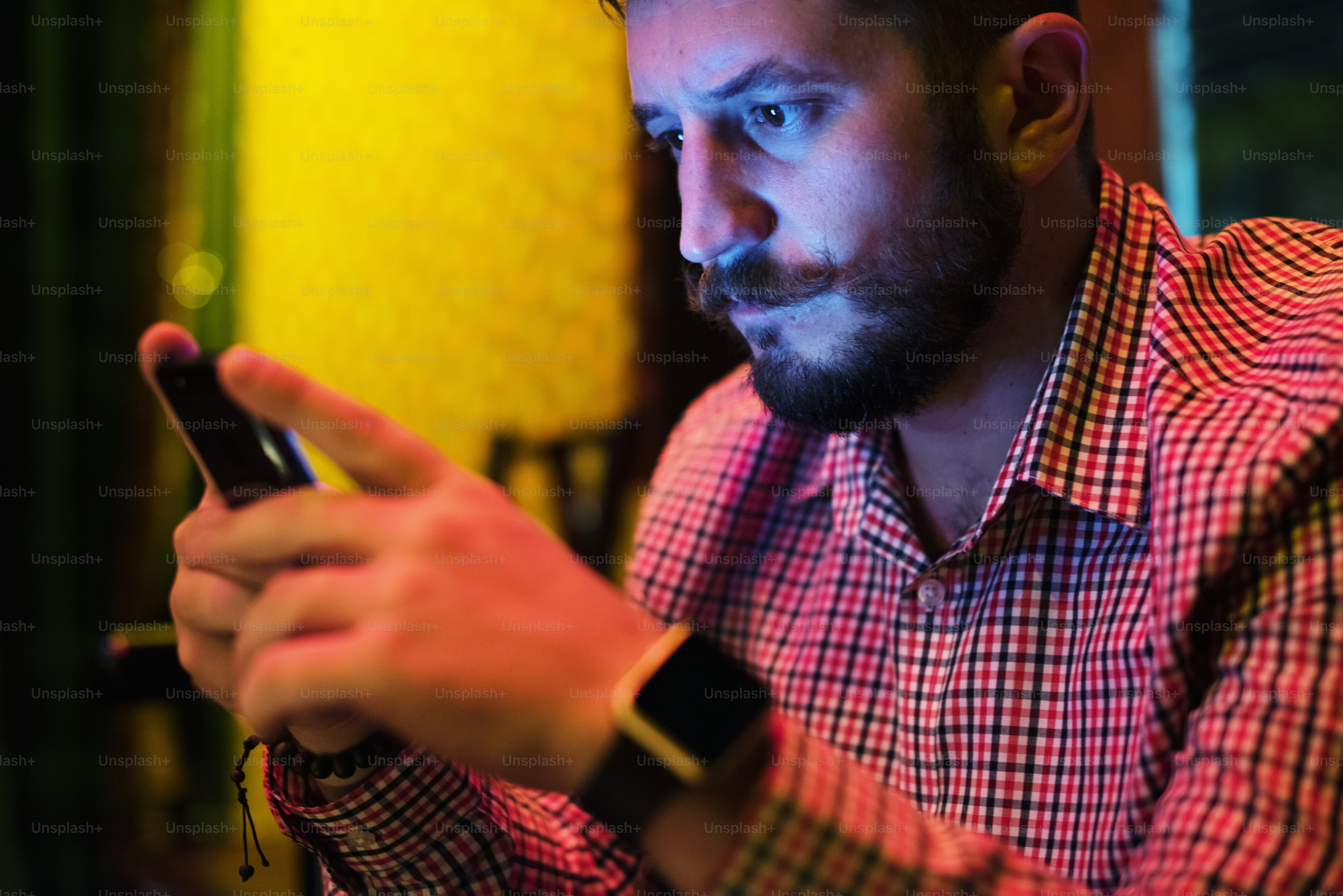 Primer plano de un hombre usando el teléfono móvil en la oscuridad con luz de larga exposición