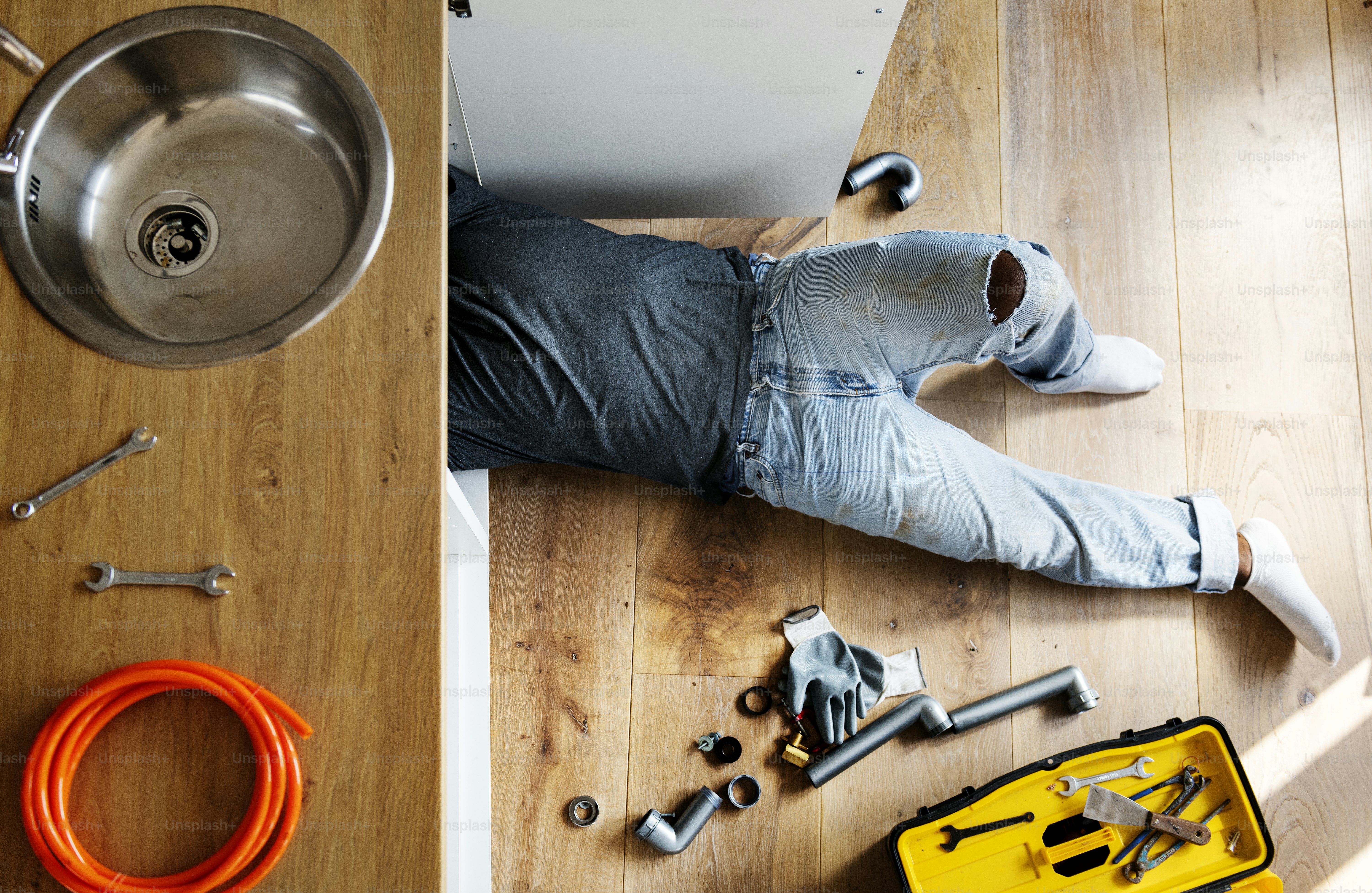 A worker fixing pipes with tools in an industrial indoor environment.