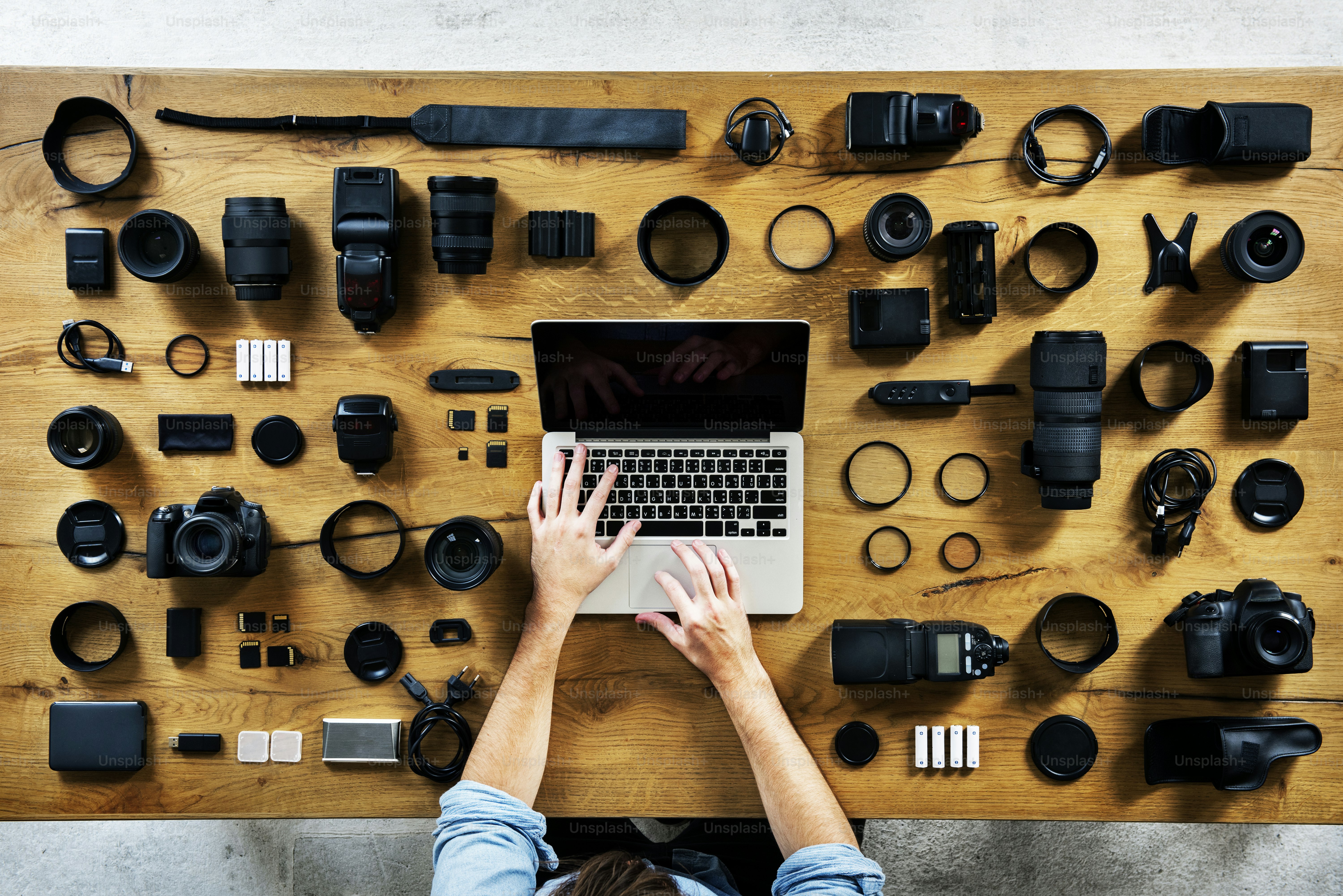 Fotógrafo usando laptop e equipamento de câmera na mesa