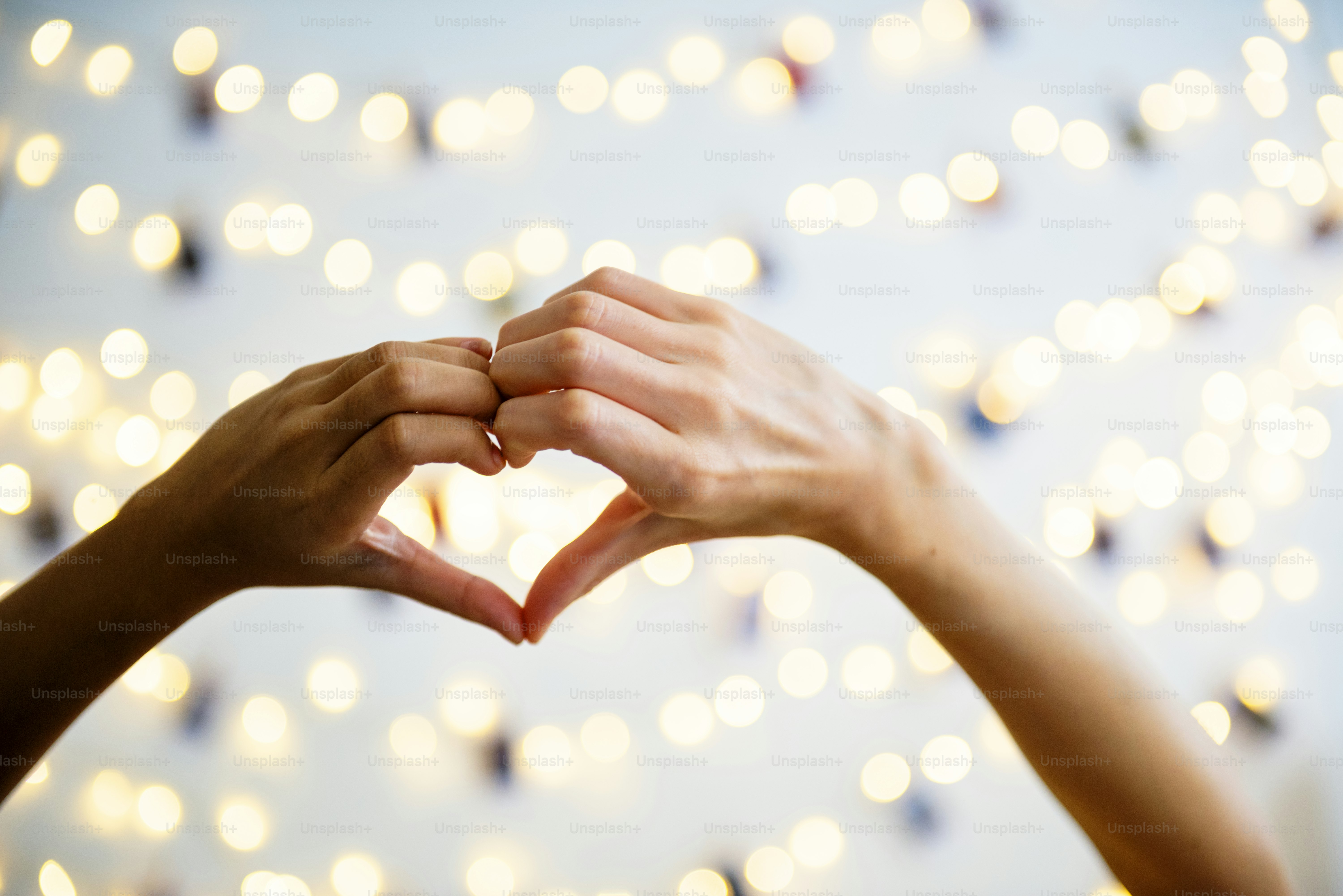 Mani a forma di cuore con luci decorative come sfondo
