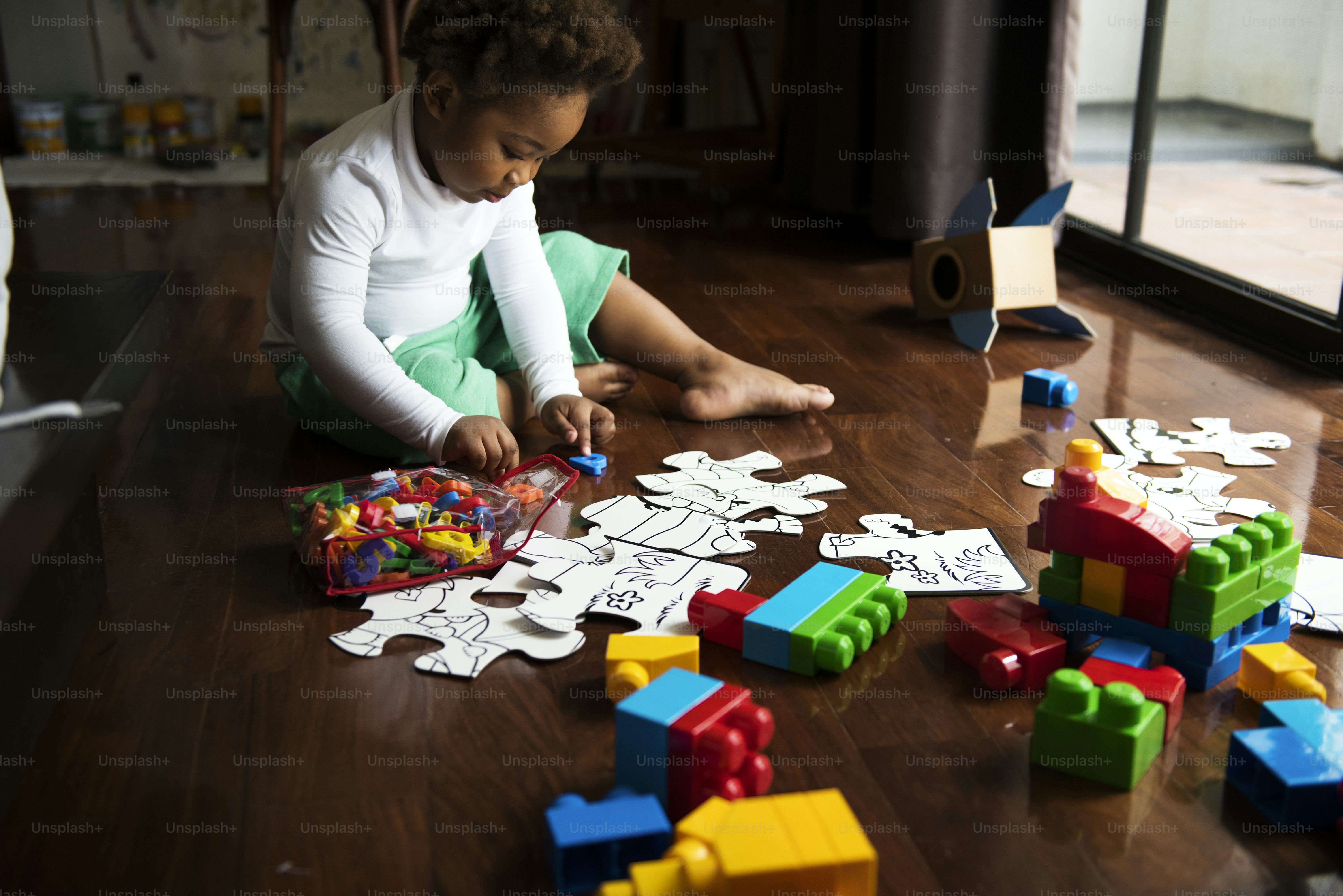 African descent kid enjoying puzzles on wooden floor