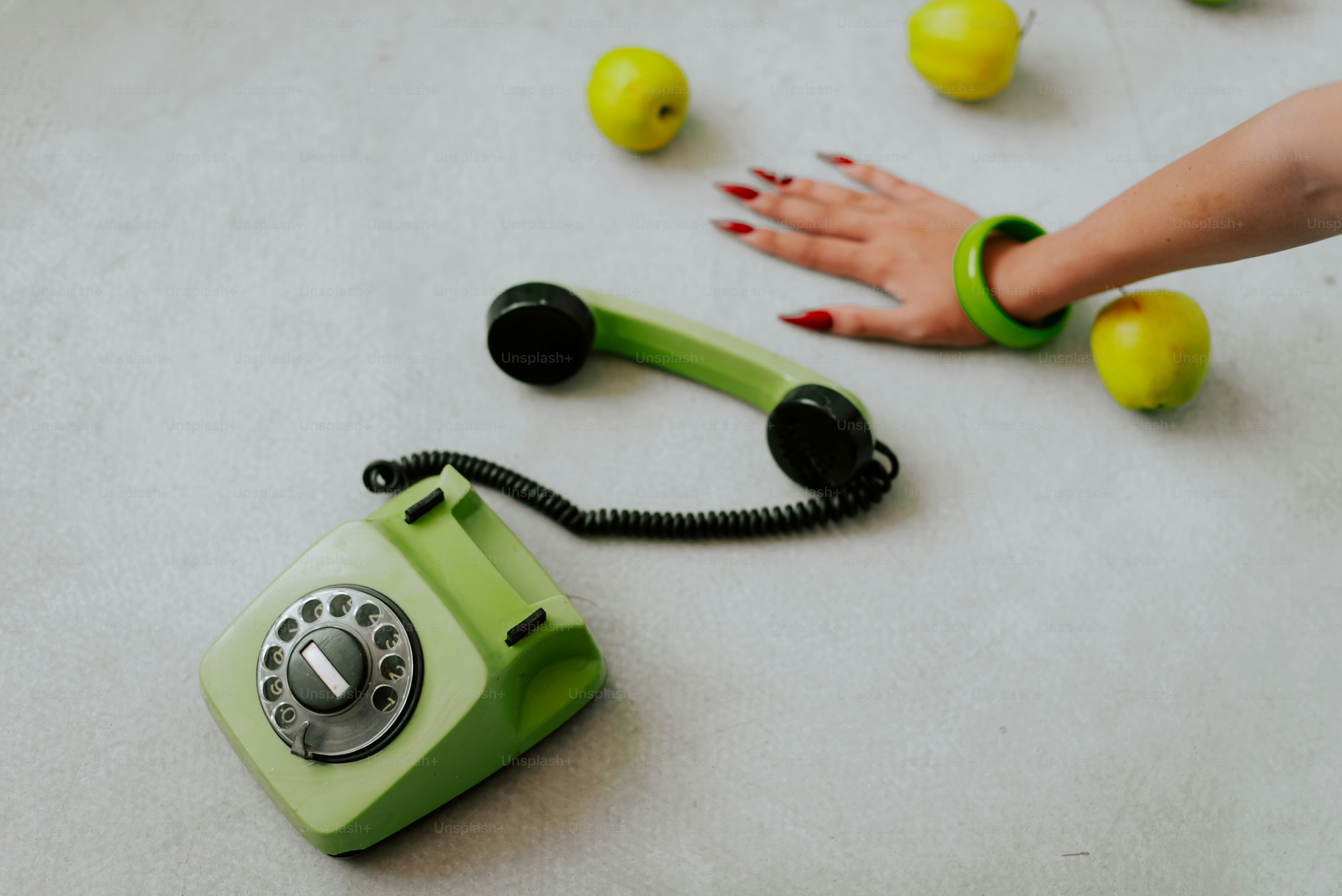 A hand reaching for a green phone on the floor
