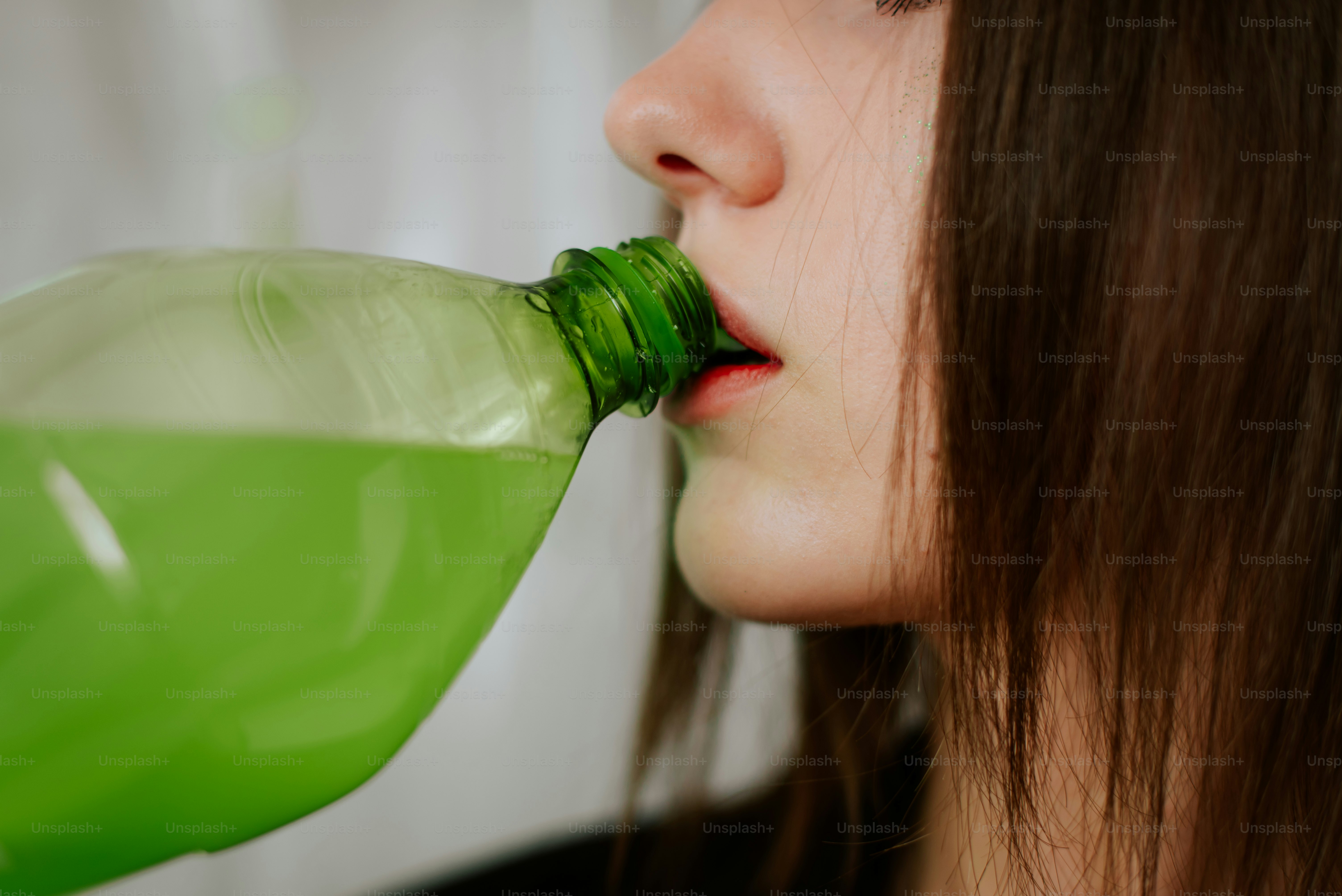 Une femme buvant dans une bouteille en plastique verte