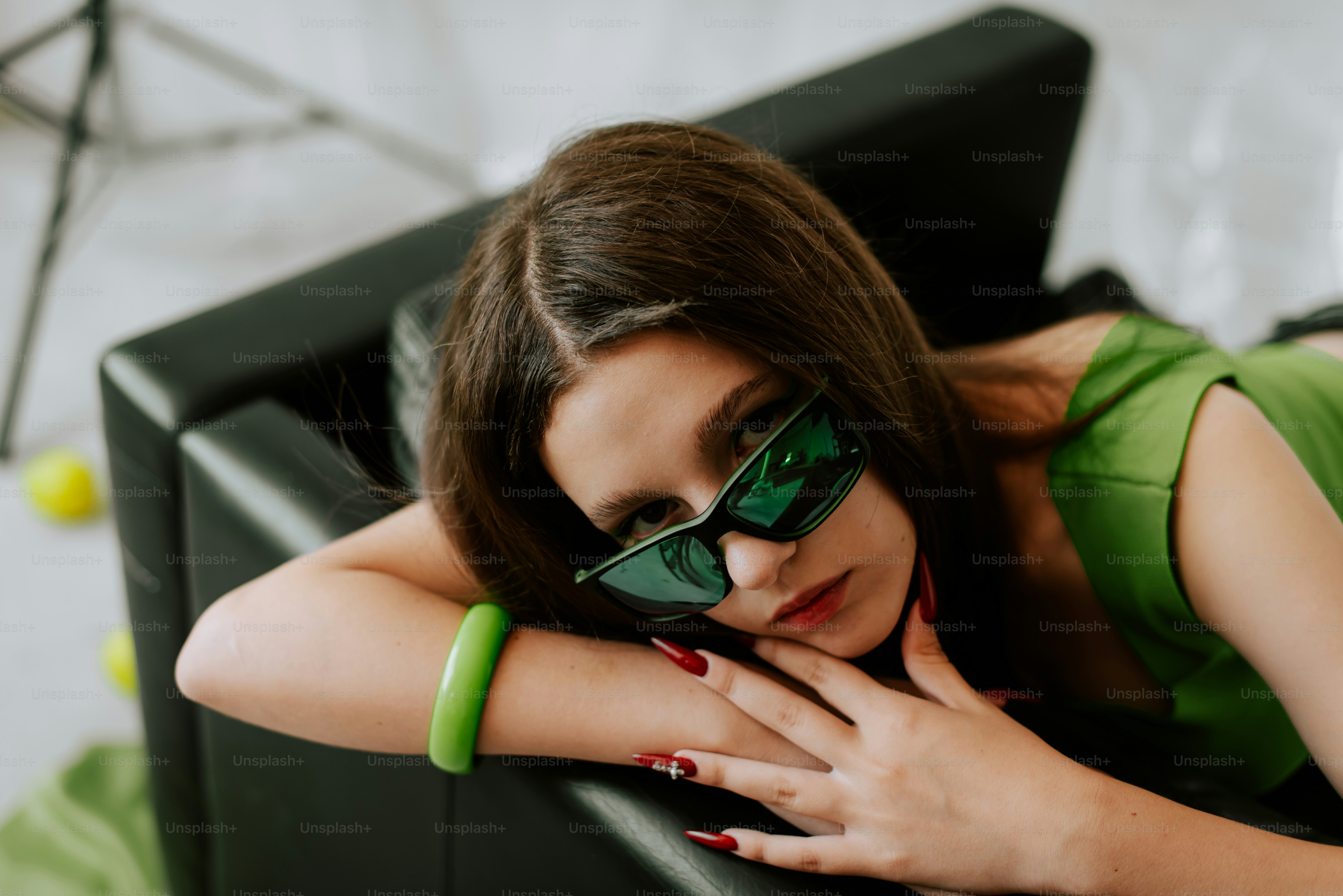 黒い椅子に横たわる緑色のトップスを着た女性