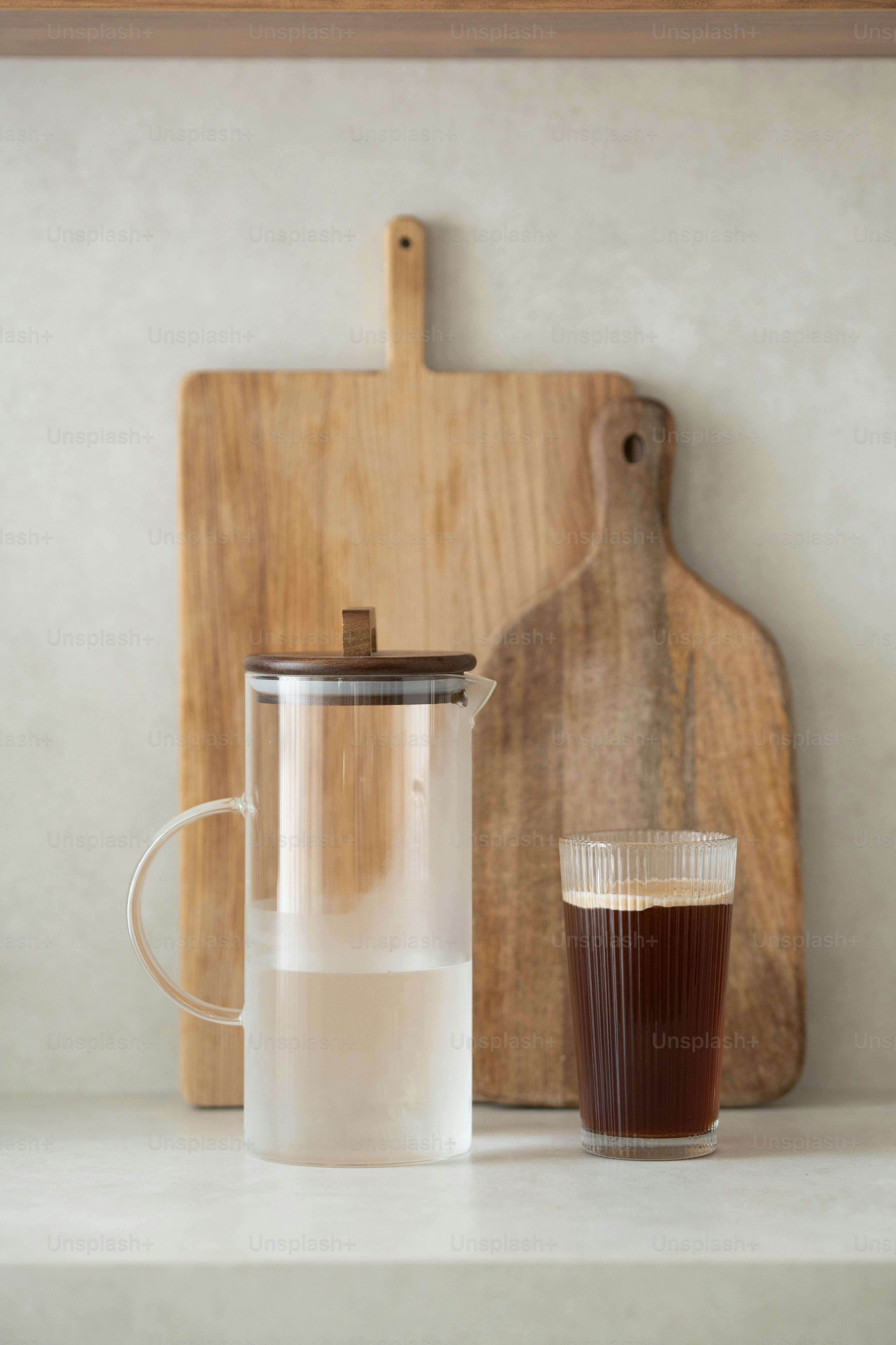 Una jarra de líquido junto a una taza de café