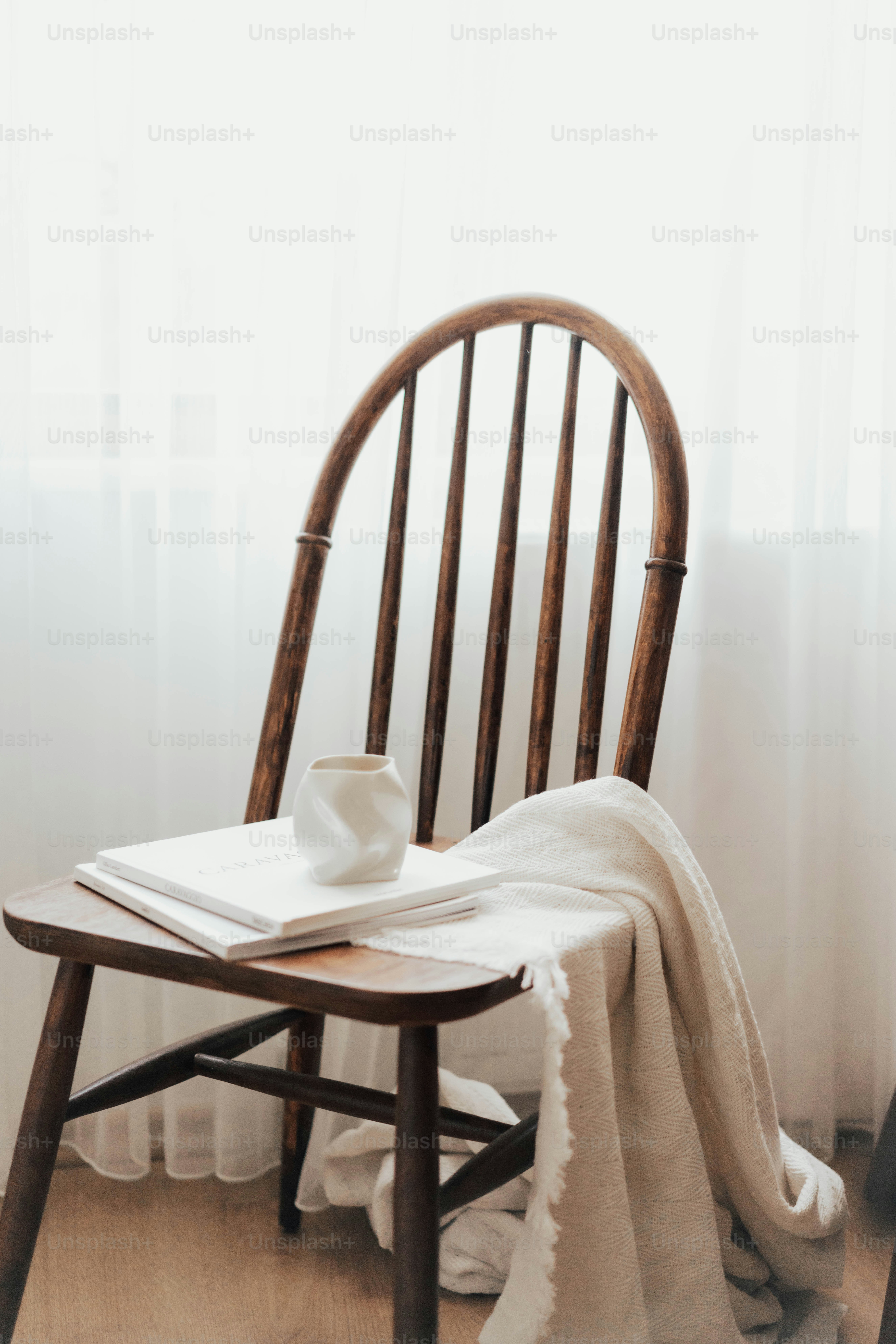 Una silla de madera con una manta blanca encima