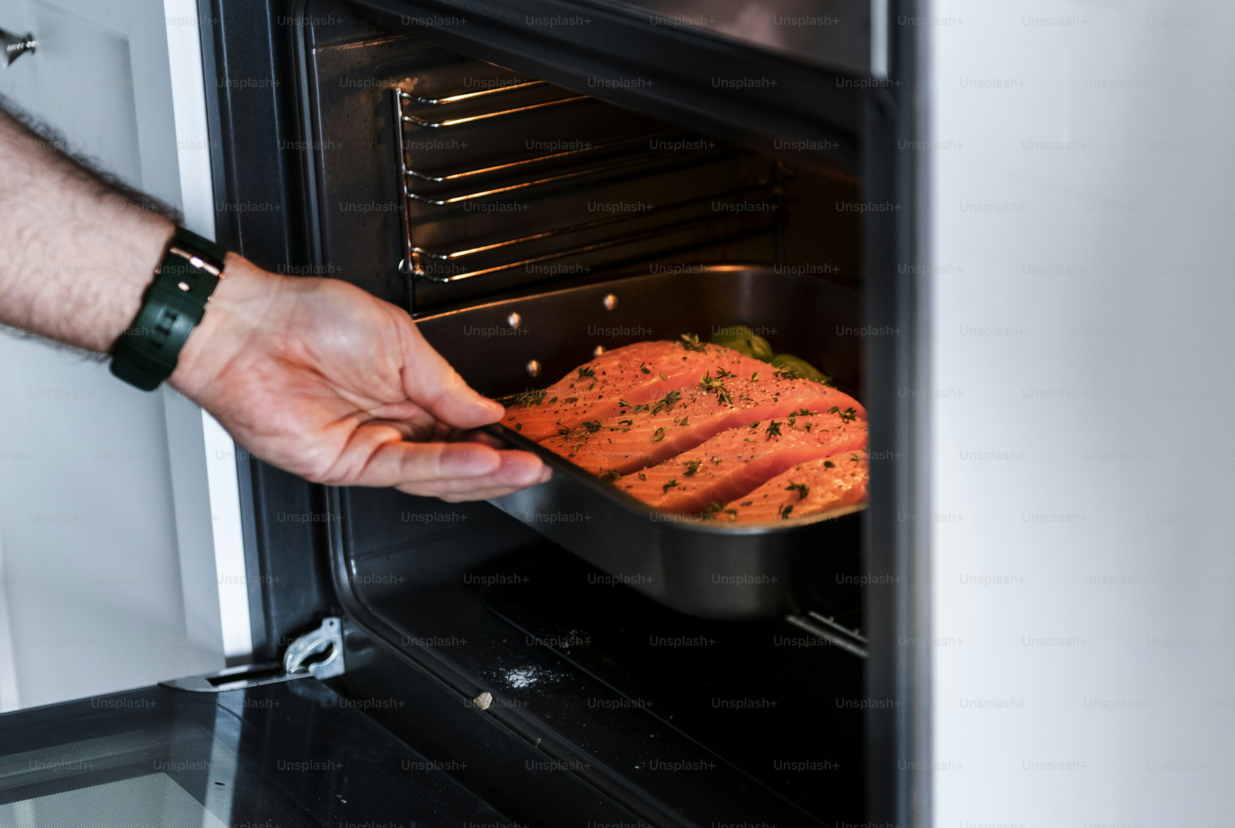 Man putting raw salmon steak into oven