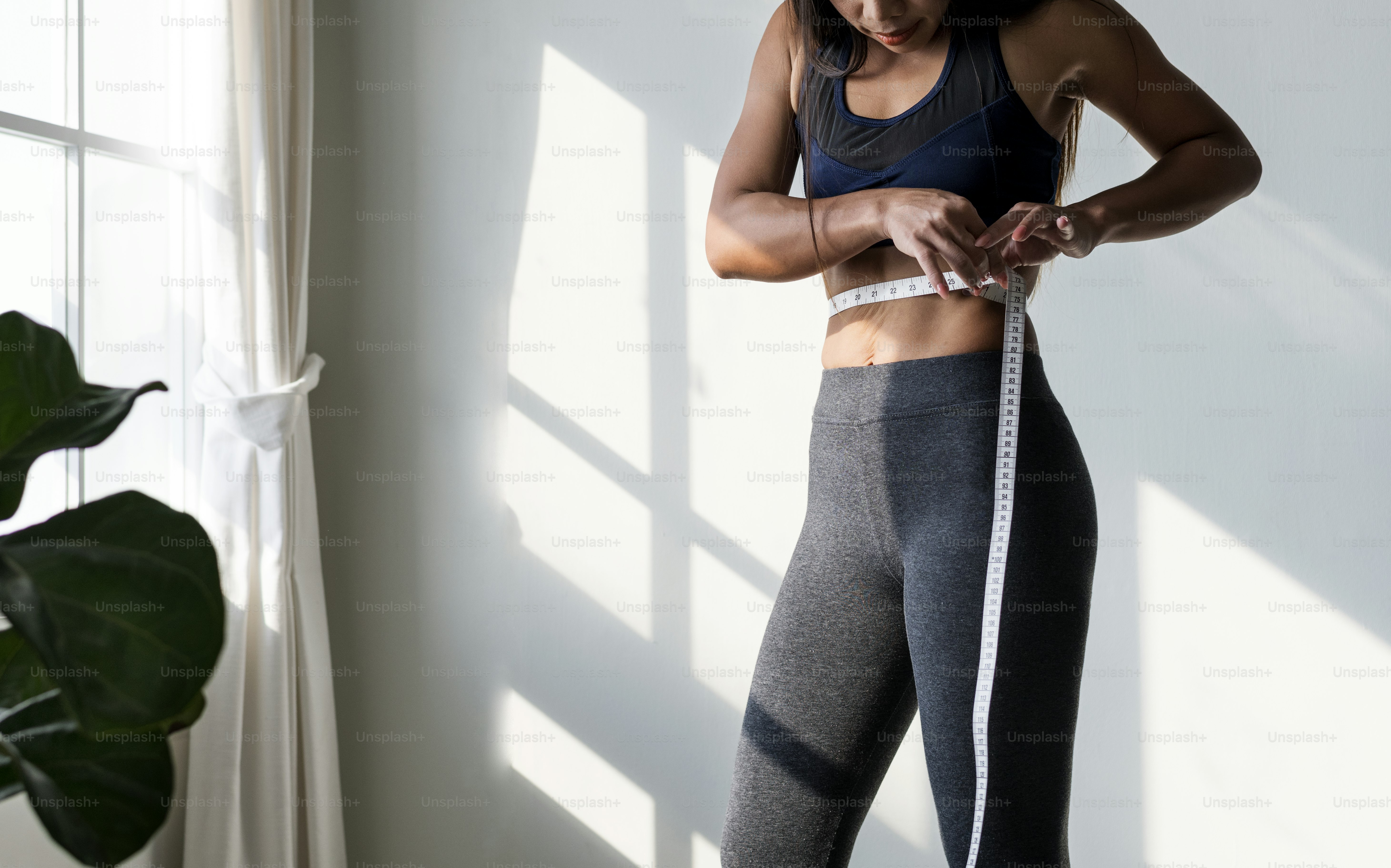 Asian woman measuring waist size