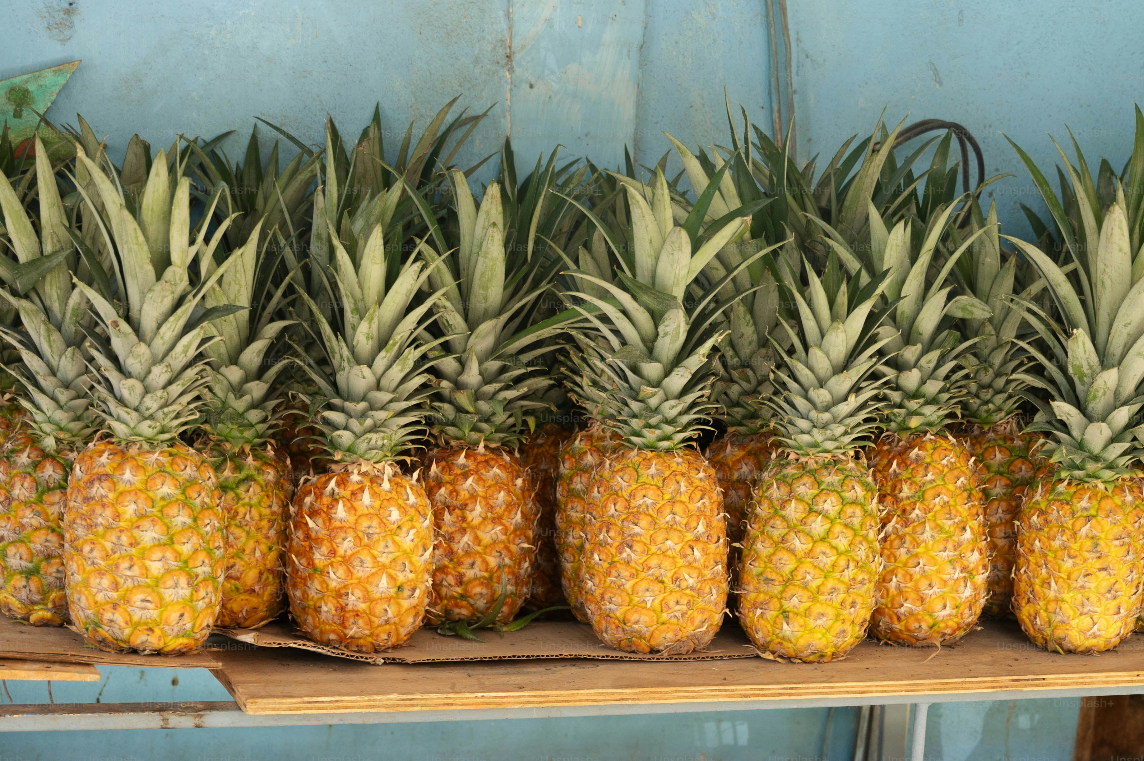 A row of pineapples sitting on top of a wooden shelf