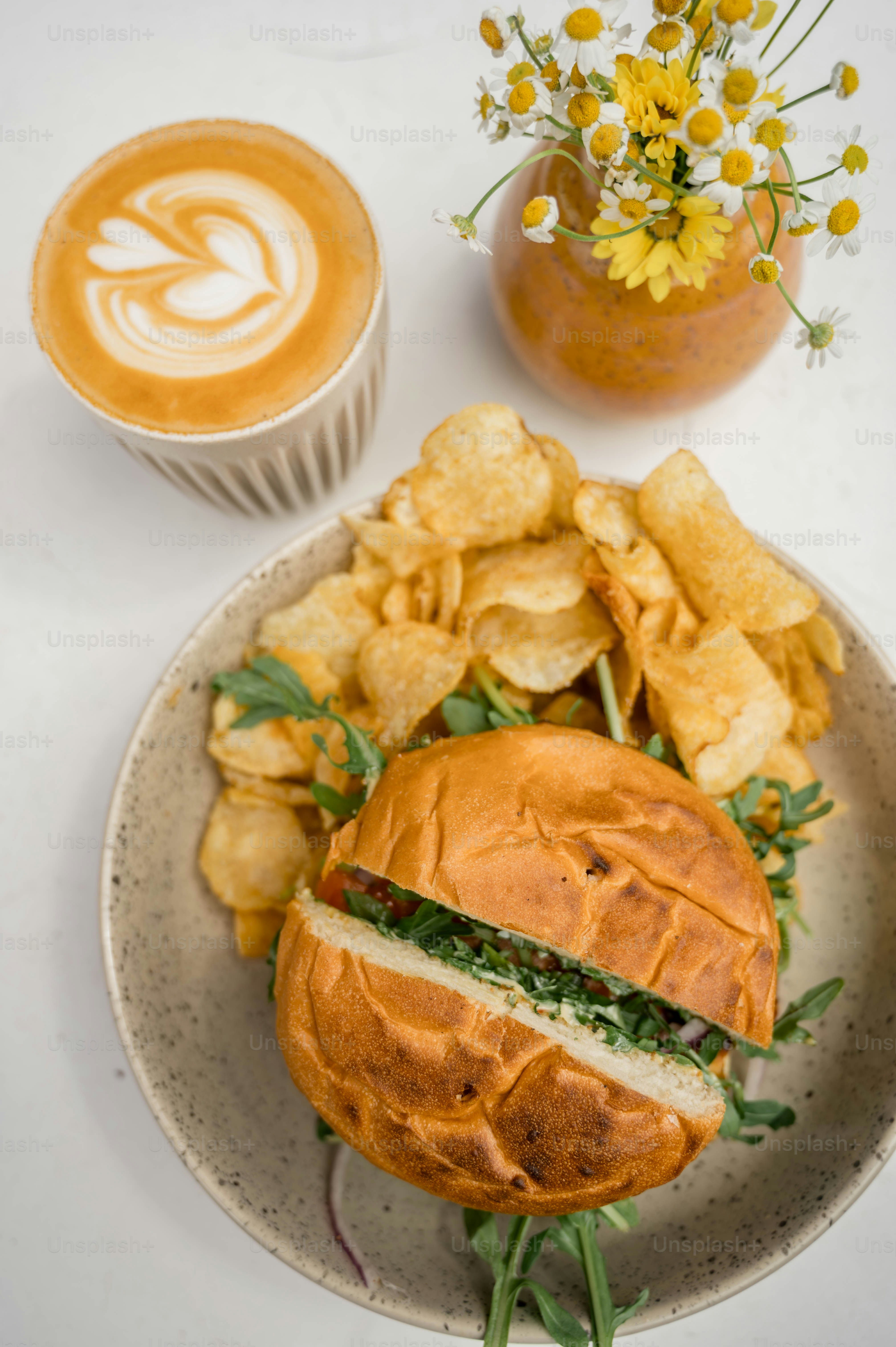 A plate with a sandwich, chips and a cup of coffee
