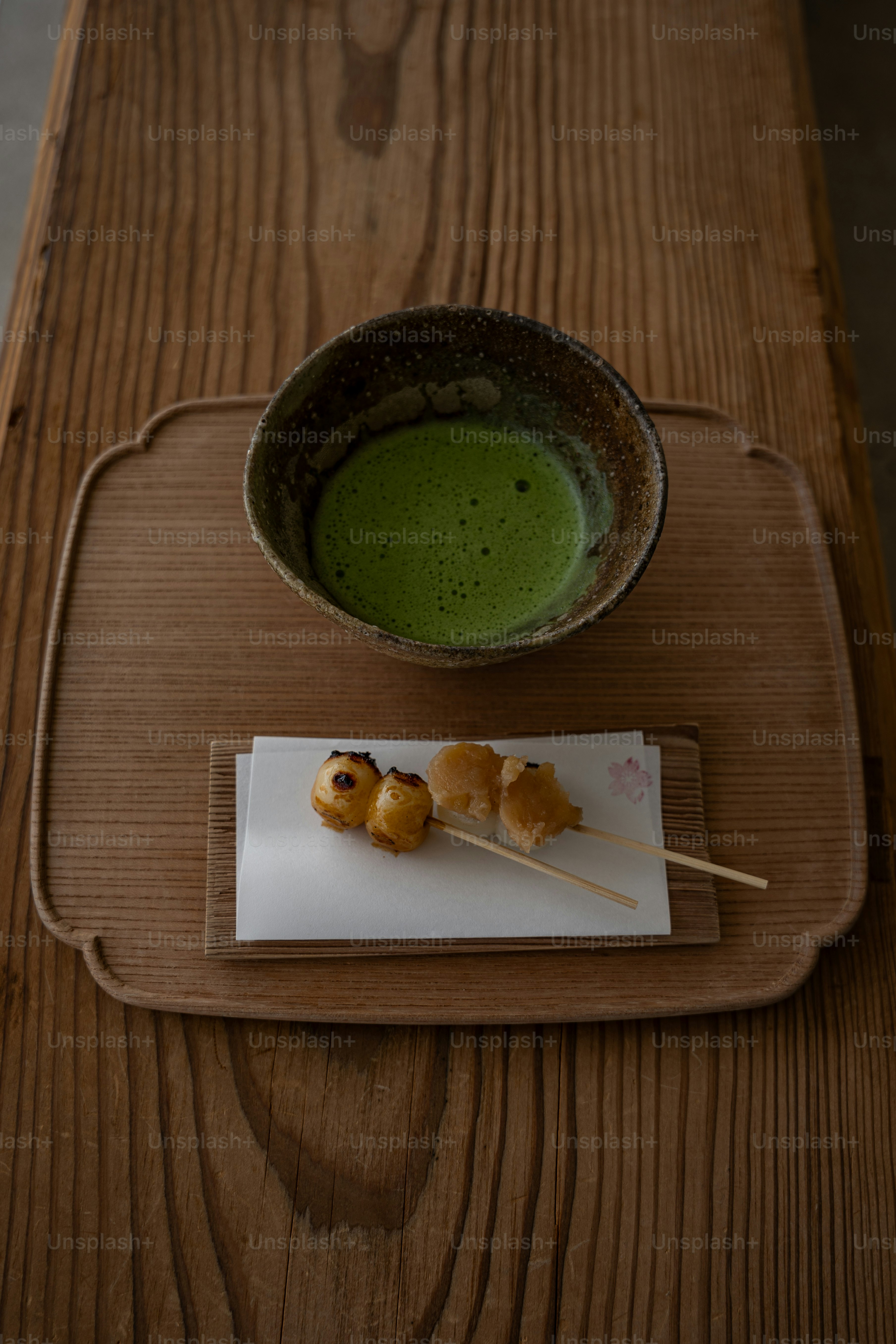 A wooden table with a plate of food and a bowl of green liquid