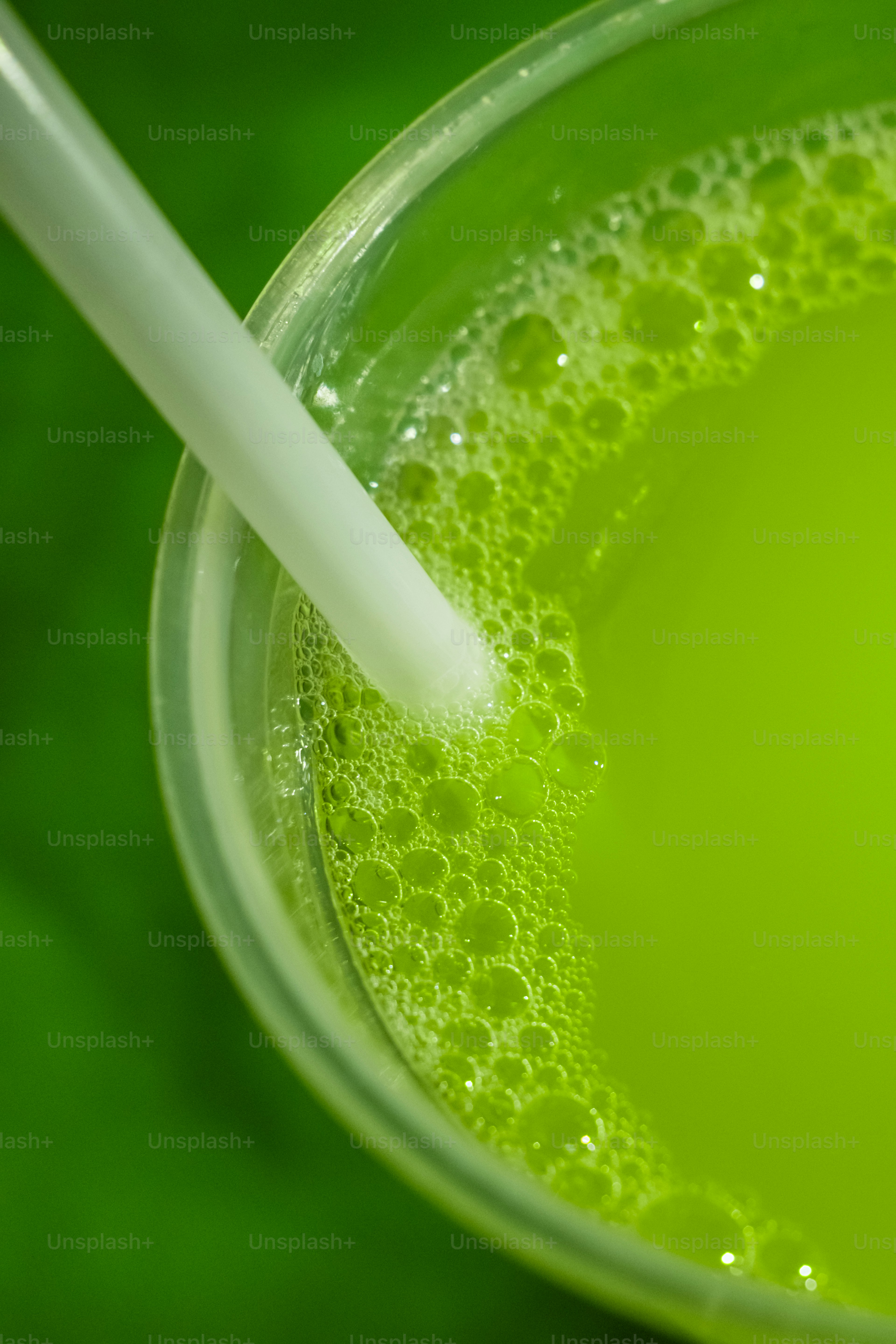 Ein Glas grüne Flüssigkeit mit einem Strohhalm darin