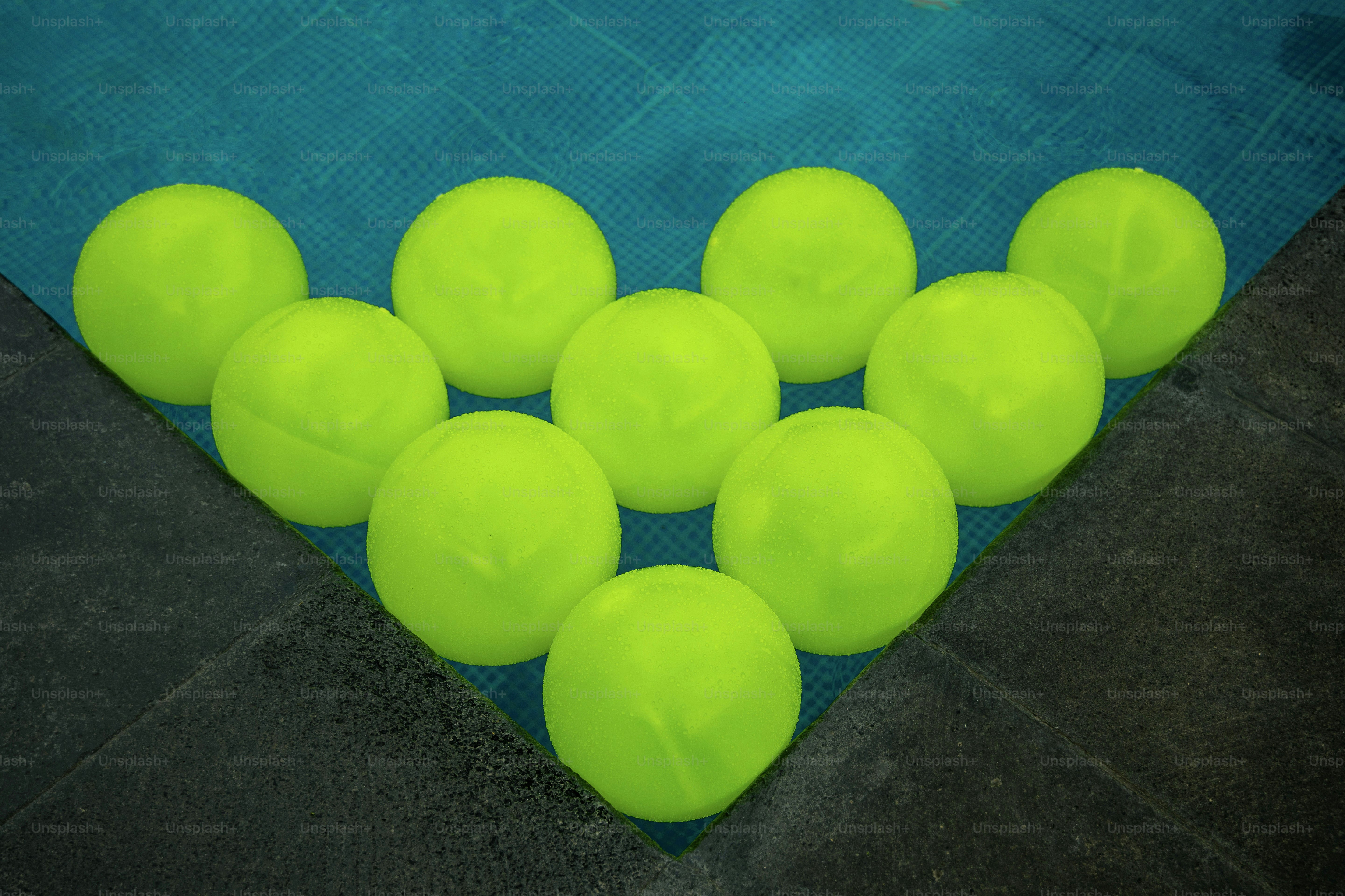 A group of neon green balls sitting on top of a pool