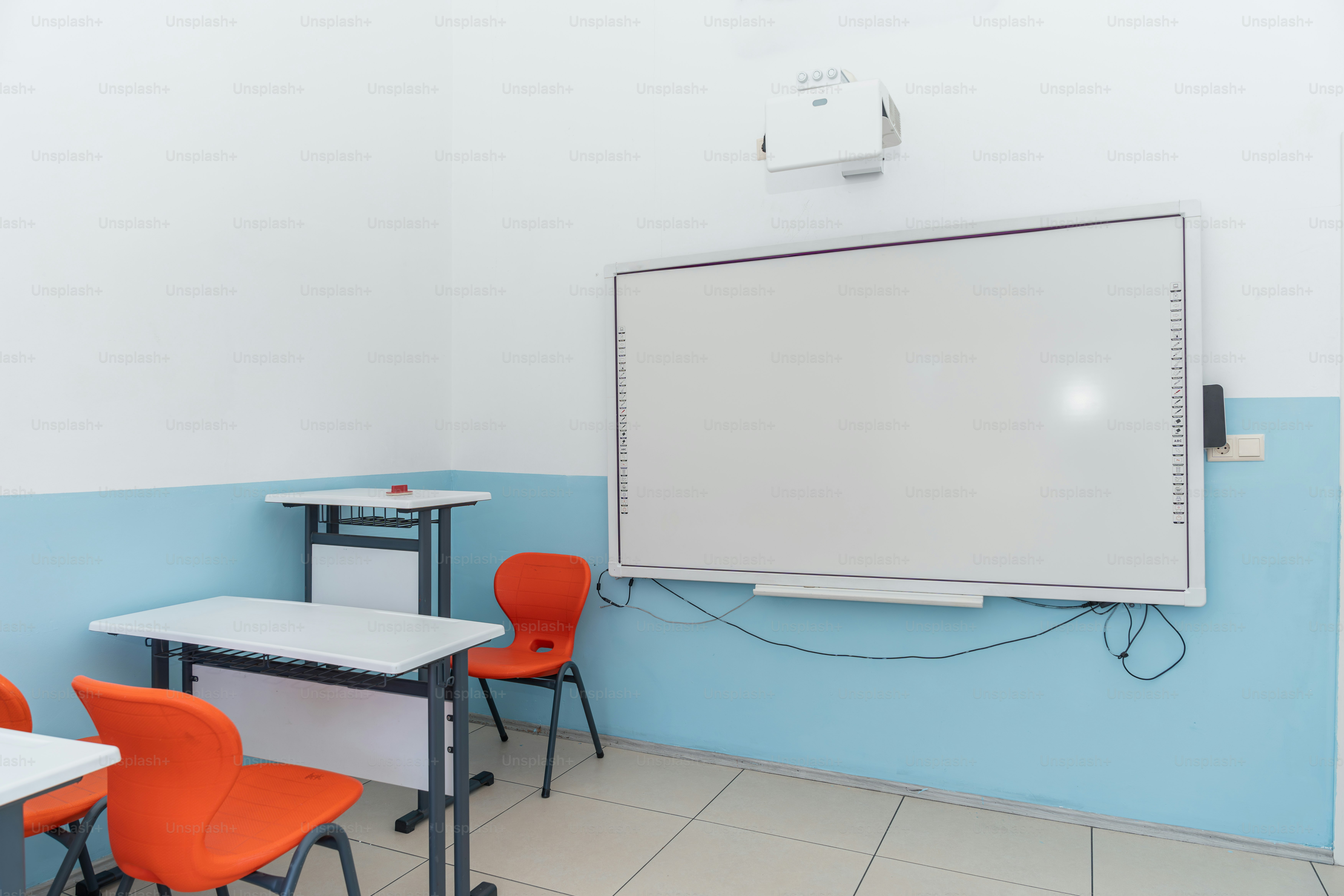 ホワイトボードとオレンジ色の椅子が置かれた教室