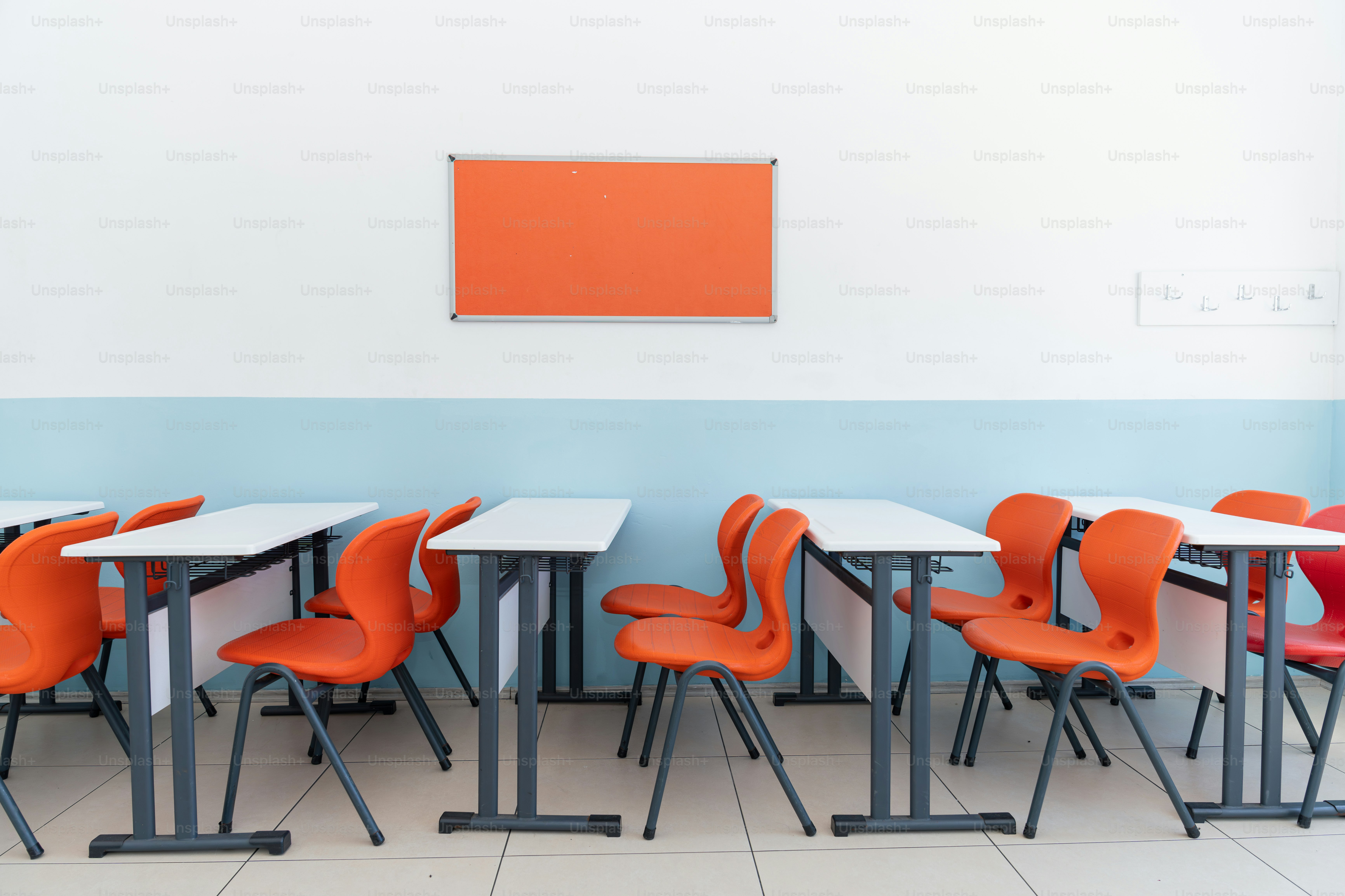 部屋にオレンジ色の椅子が並ぶ机