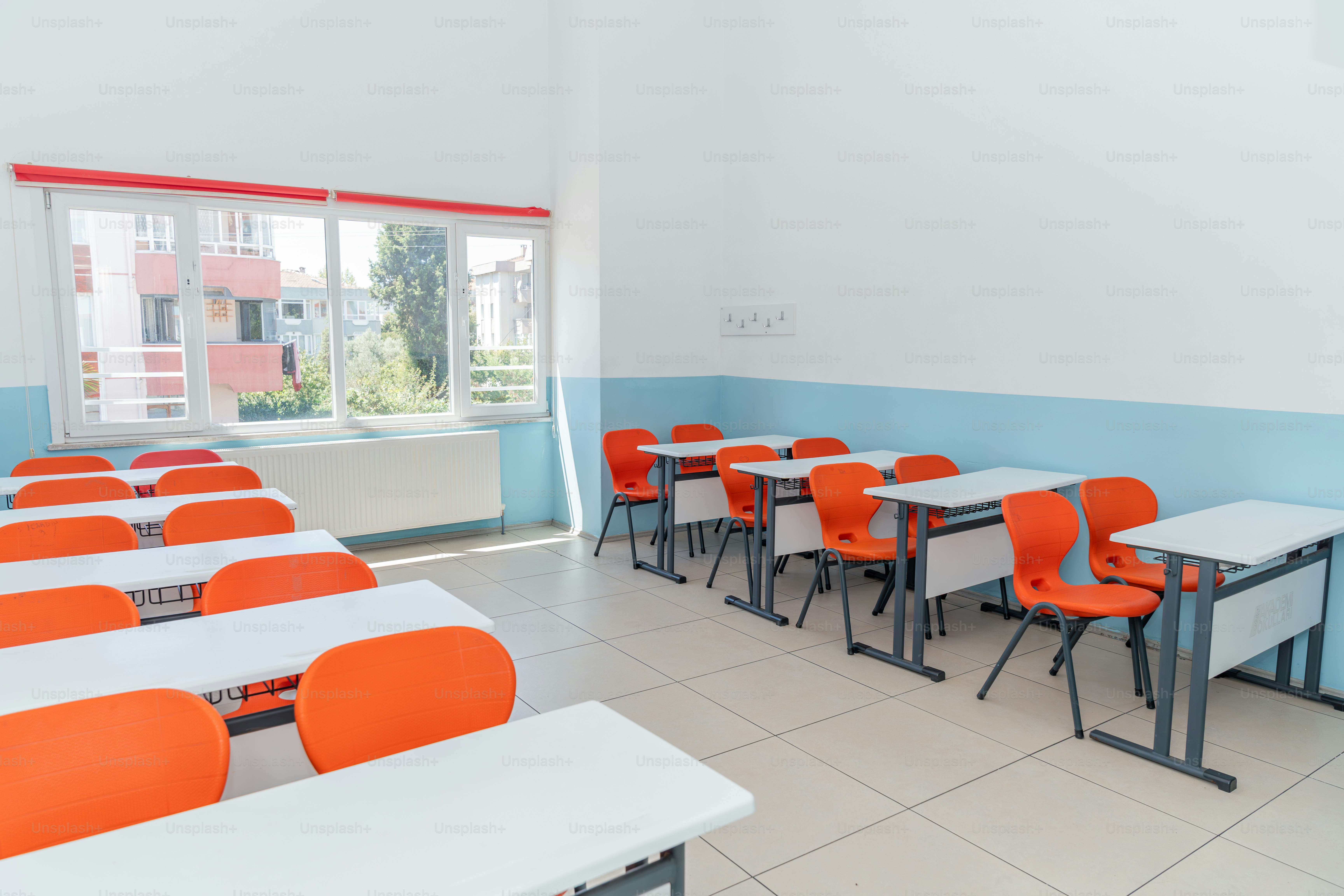 A classroom with orange chairs and white desks