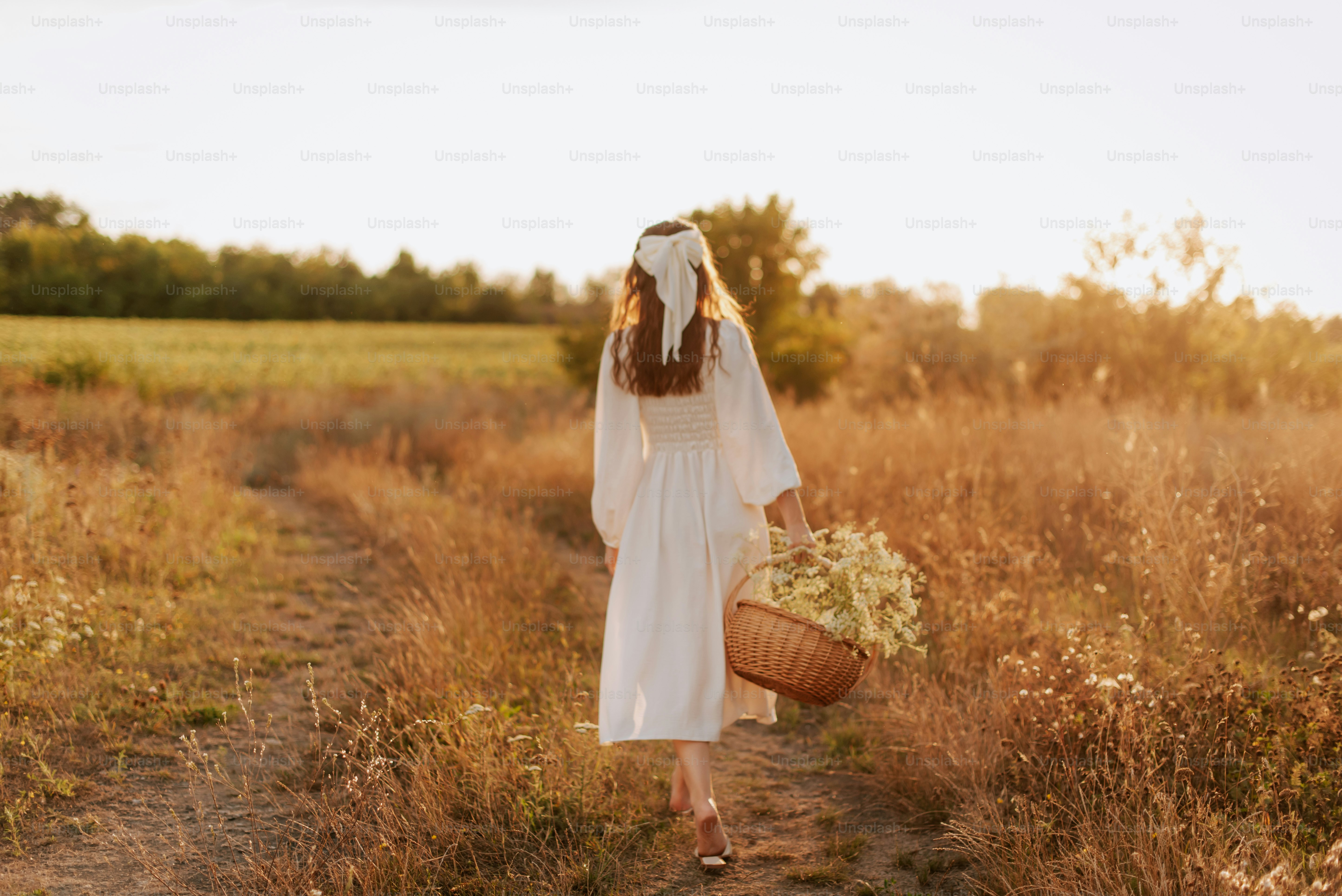 A woman in a white dress standing by a lake photo – Sunset Image on ...