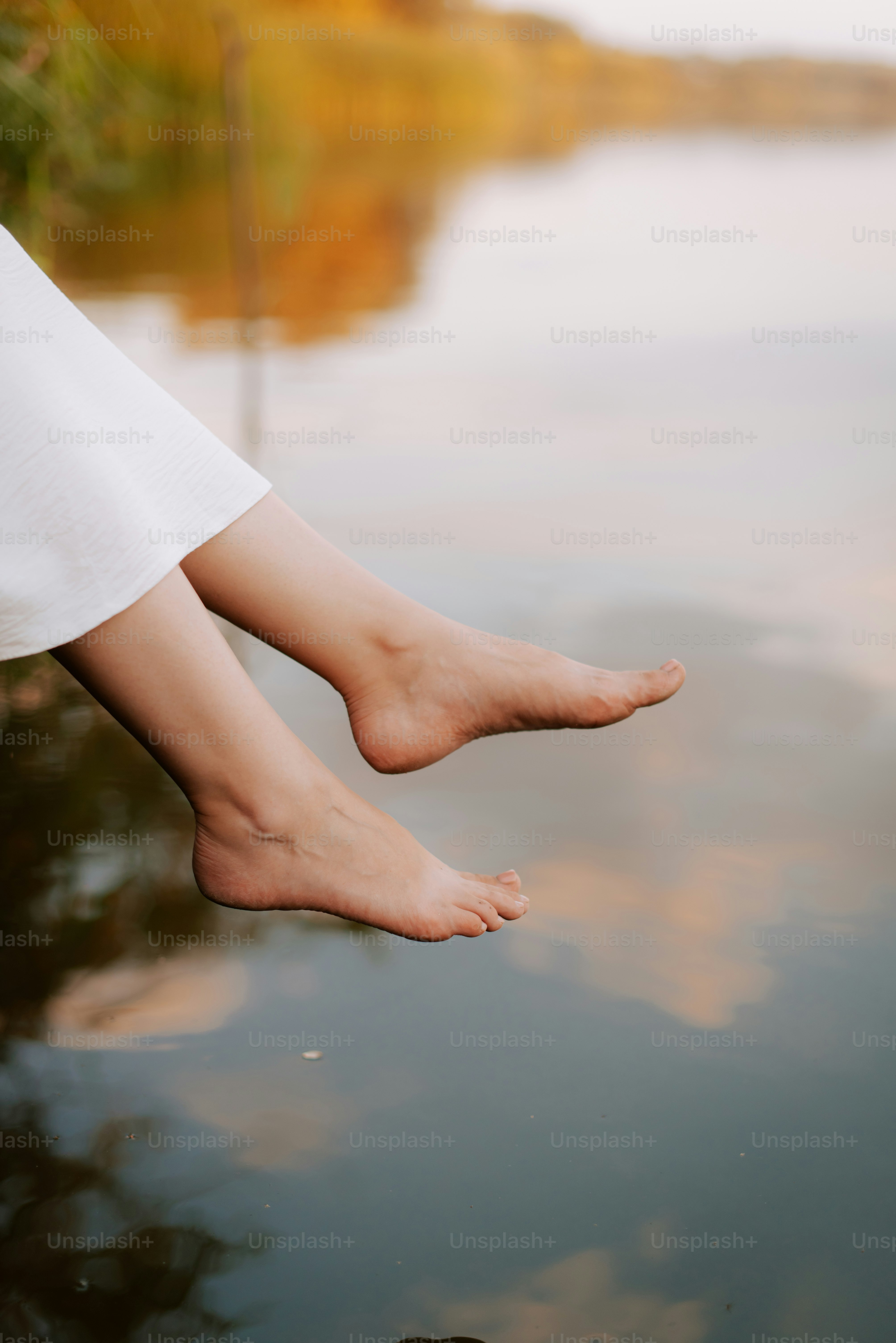 A woman's bare feet hanging over a body of water