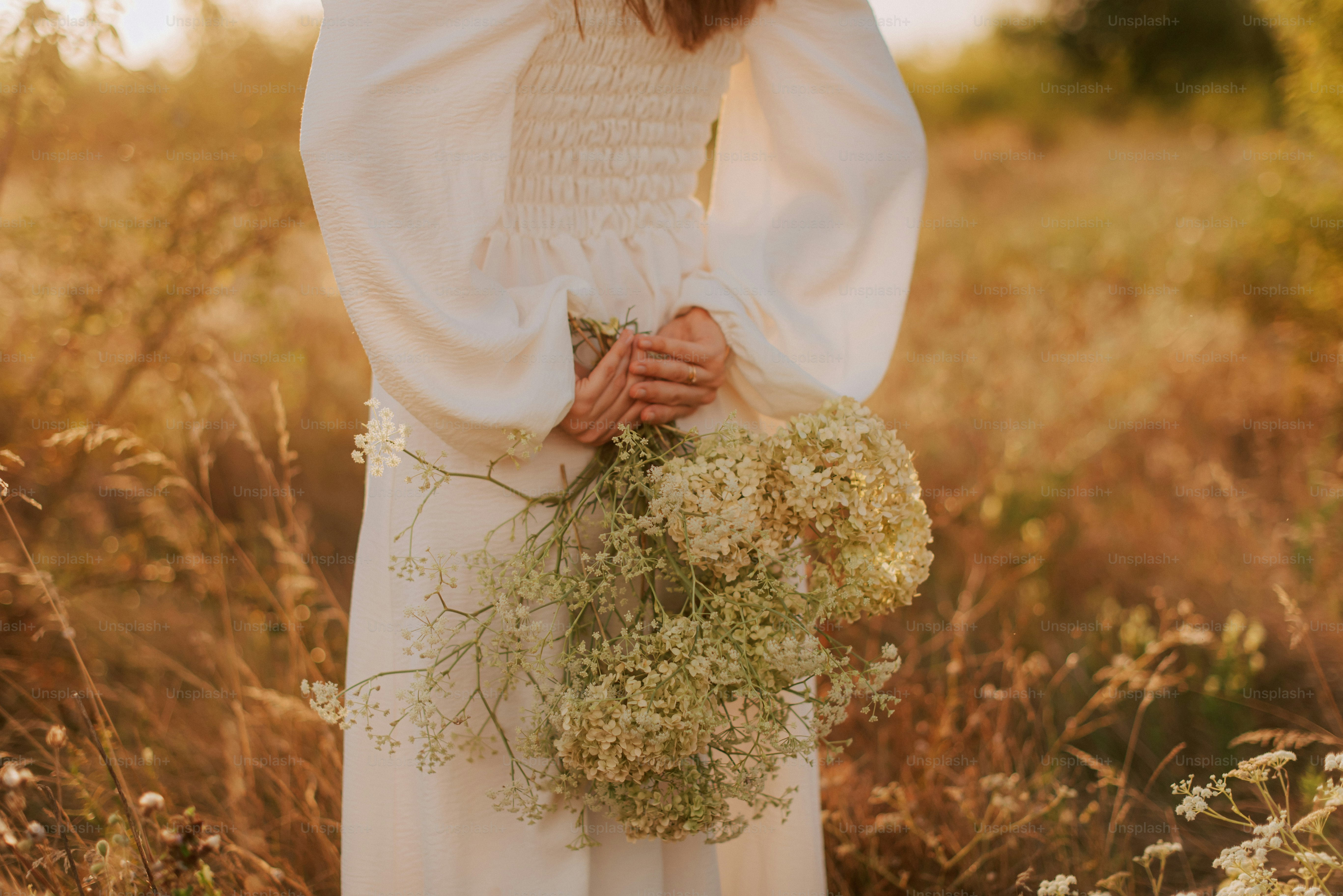 A woman standing in a field holding a bouquet of flowers photo – Meadow ...