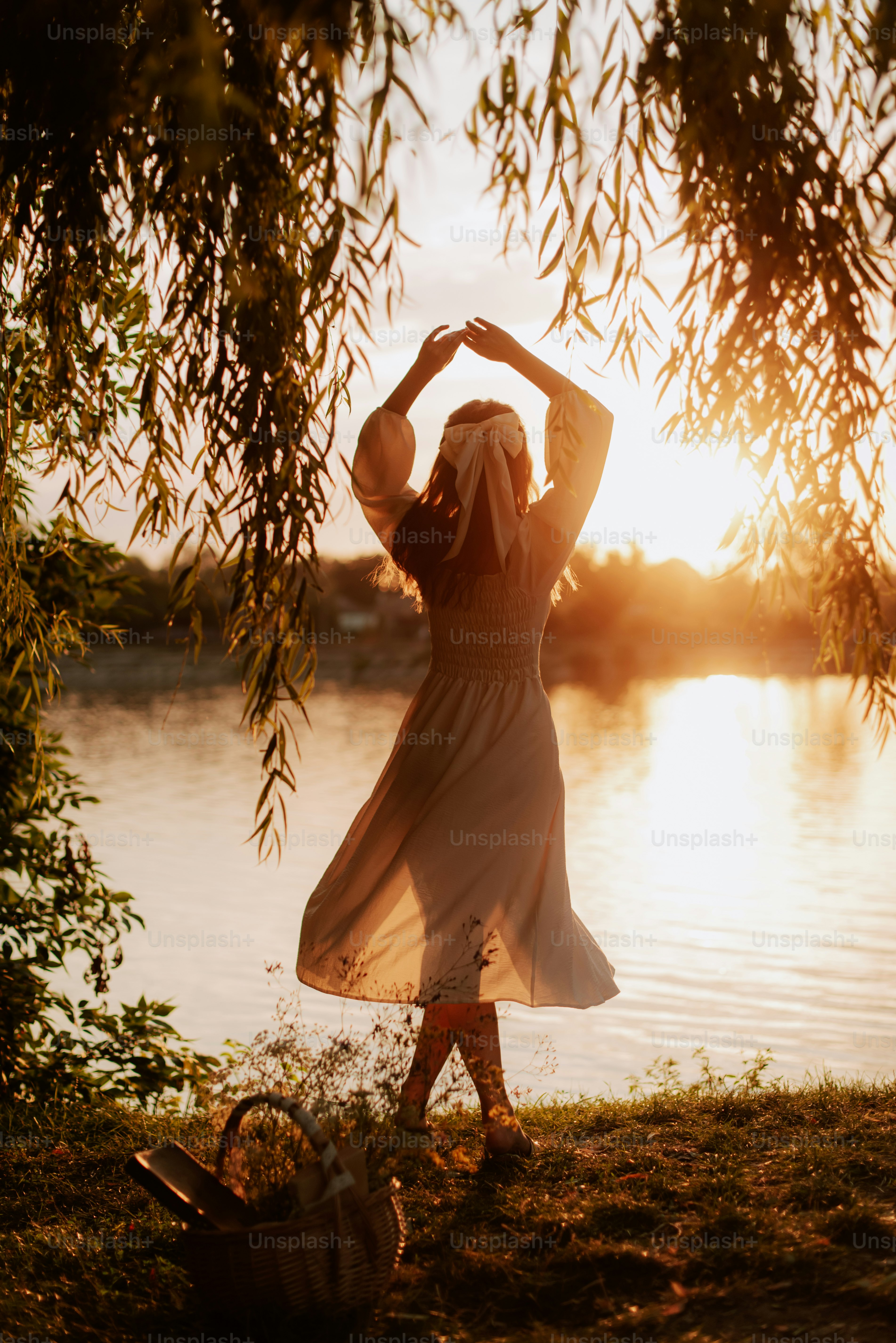 A woman standing next to a lake at sunset