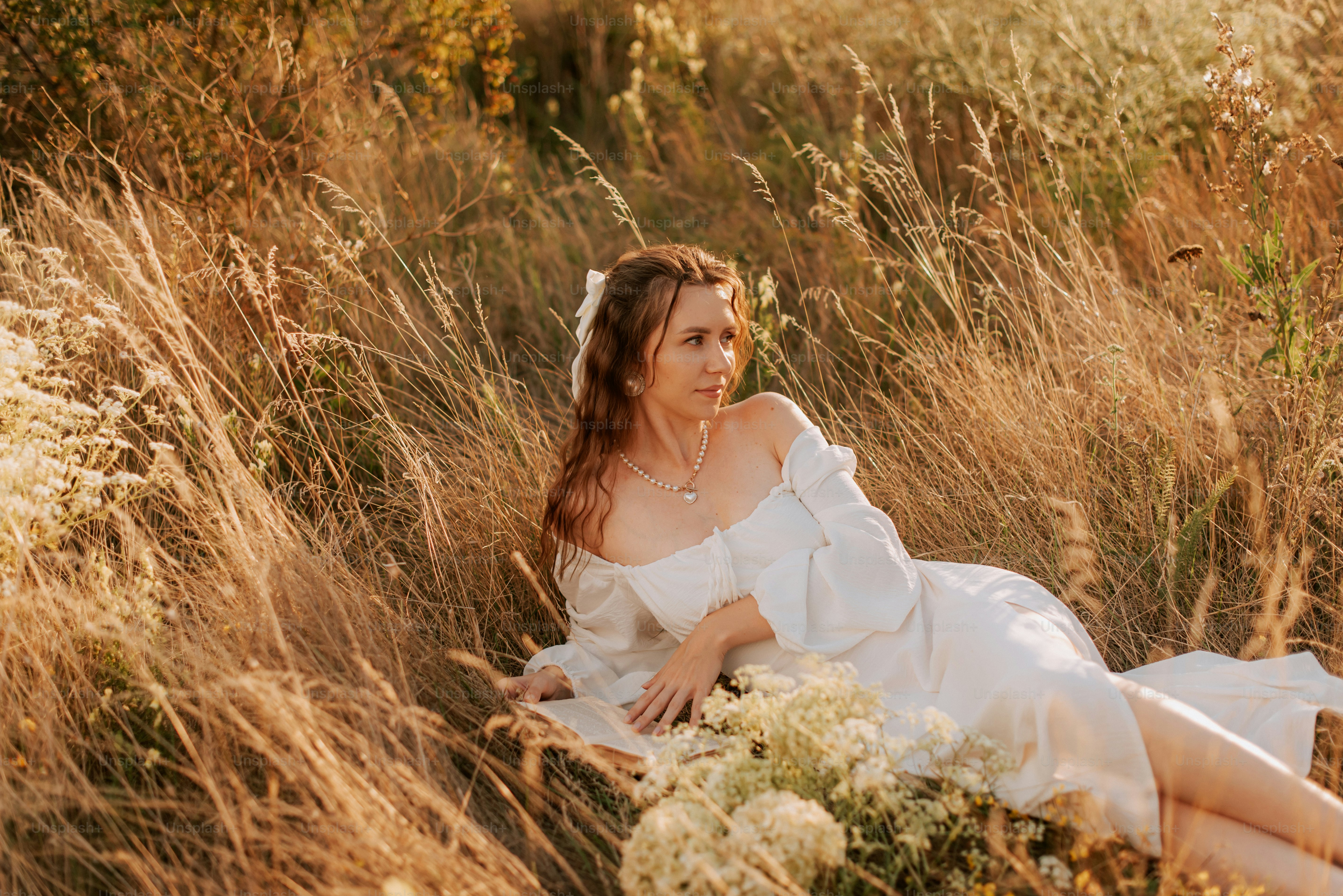 A woman in a white dress sitting in a field photo – Simple living Image ...
